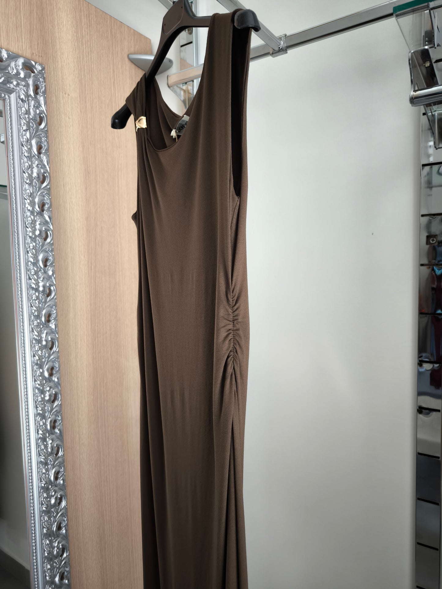 Abito lungo marrone elegante con arricciature laterali e due spacchi, appeso su gruccia in una boutique.