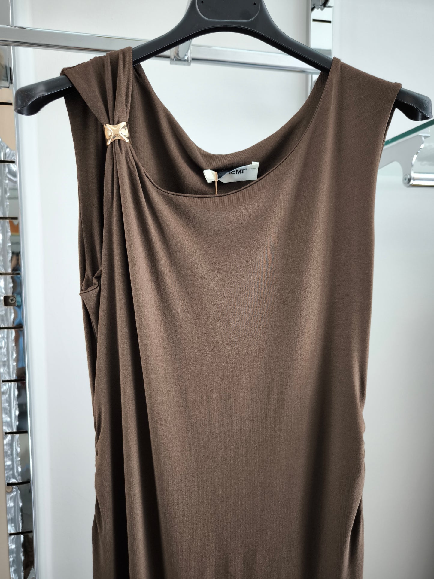 Abito lungo marrone elegante con arricciature laterali e due spacchi, appeso su gruccia in una boutique.