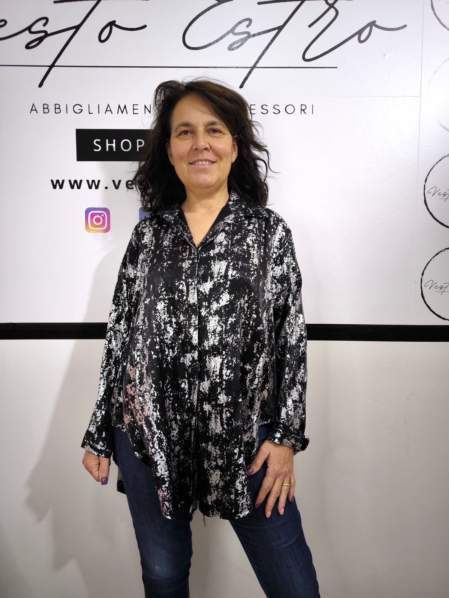 Camicia oversize da donna nera con stampa astratta argentata, indossata con jeans. Look moderno ed elegante.