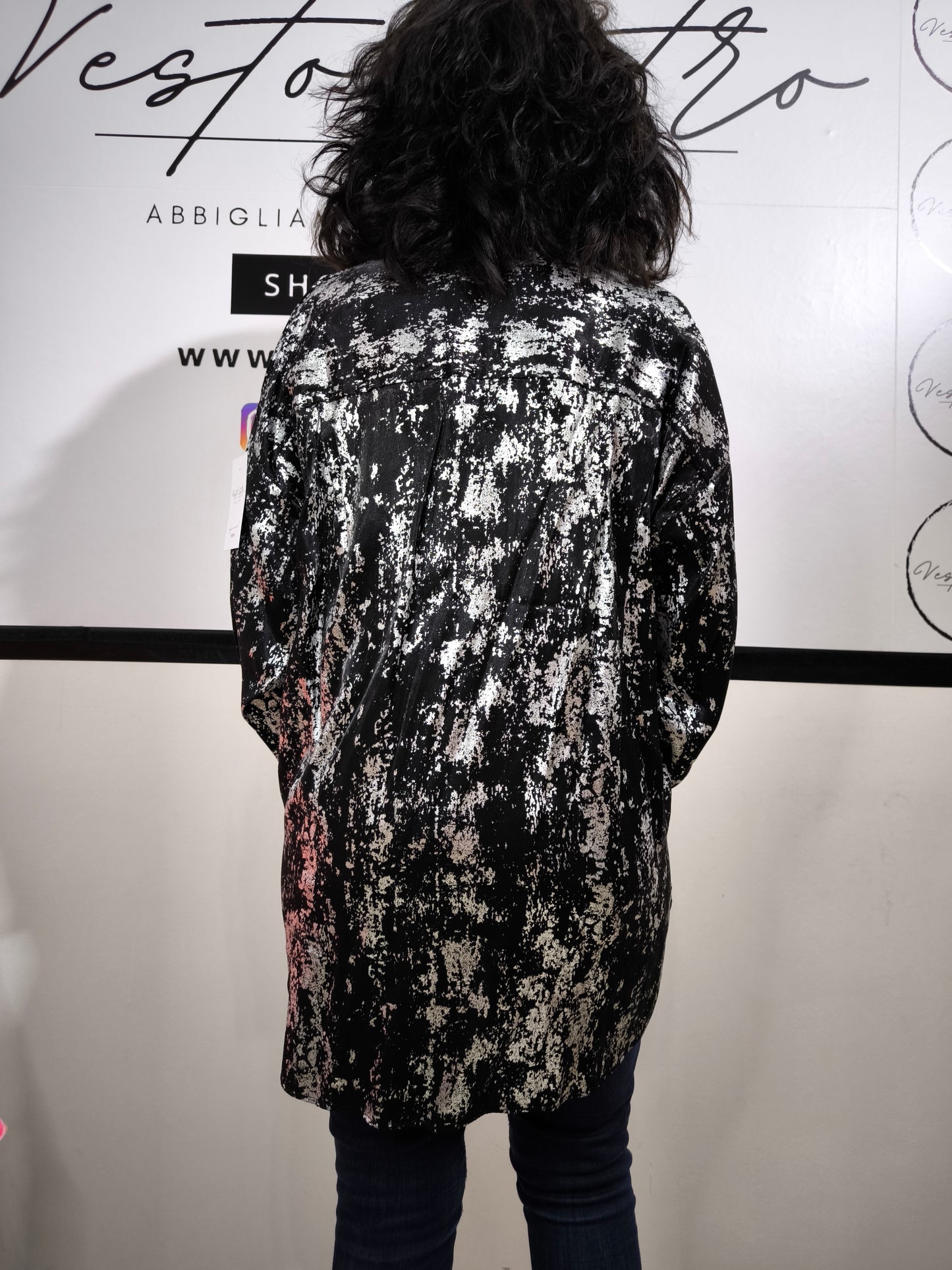 Camicia oversize da donna nera con stampa astratta argentata, indossata con jeans. Look moderno ed elegante.