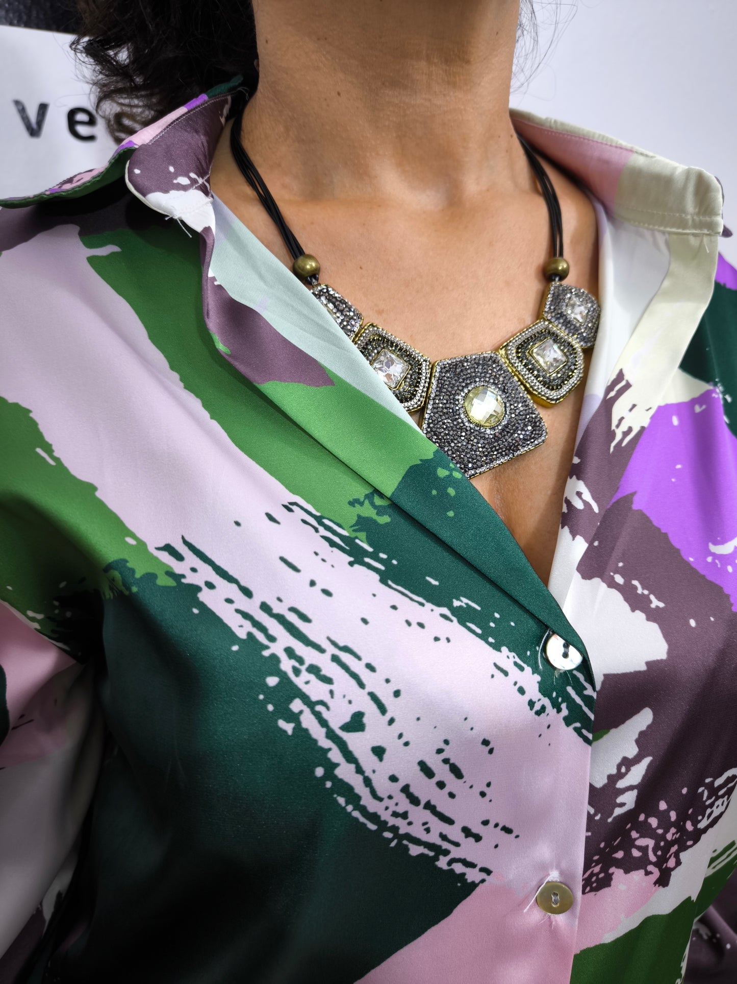 Donna che indossa una camicia satinata a fantasia astratta multicolore con bottoni e colletto classico.