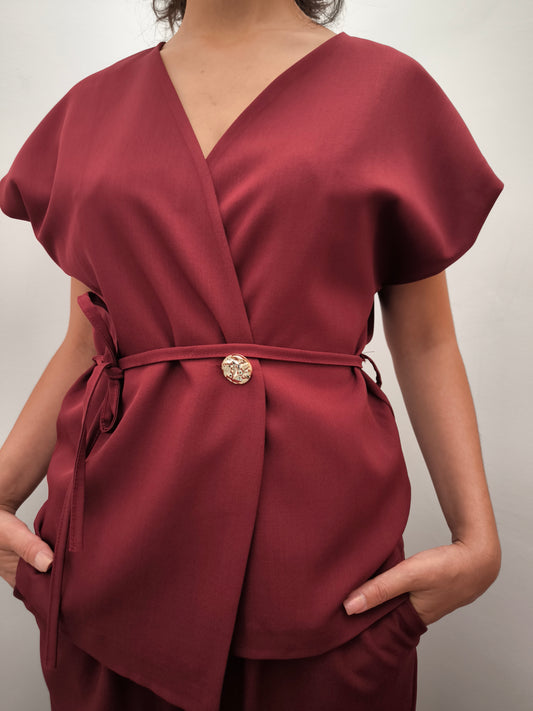 Donna che indossa completo elegante AURA in tessuto bordeaux, con giacca foderata a manica corta