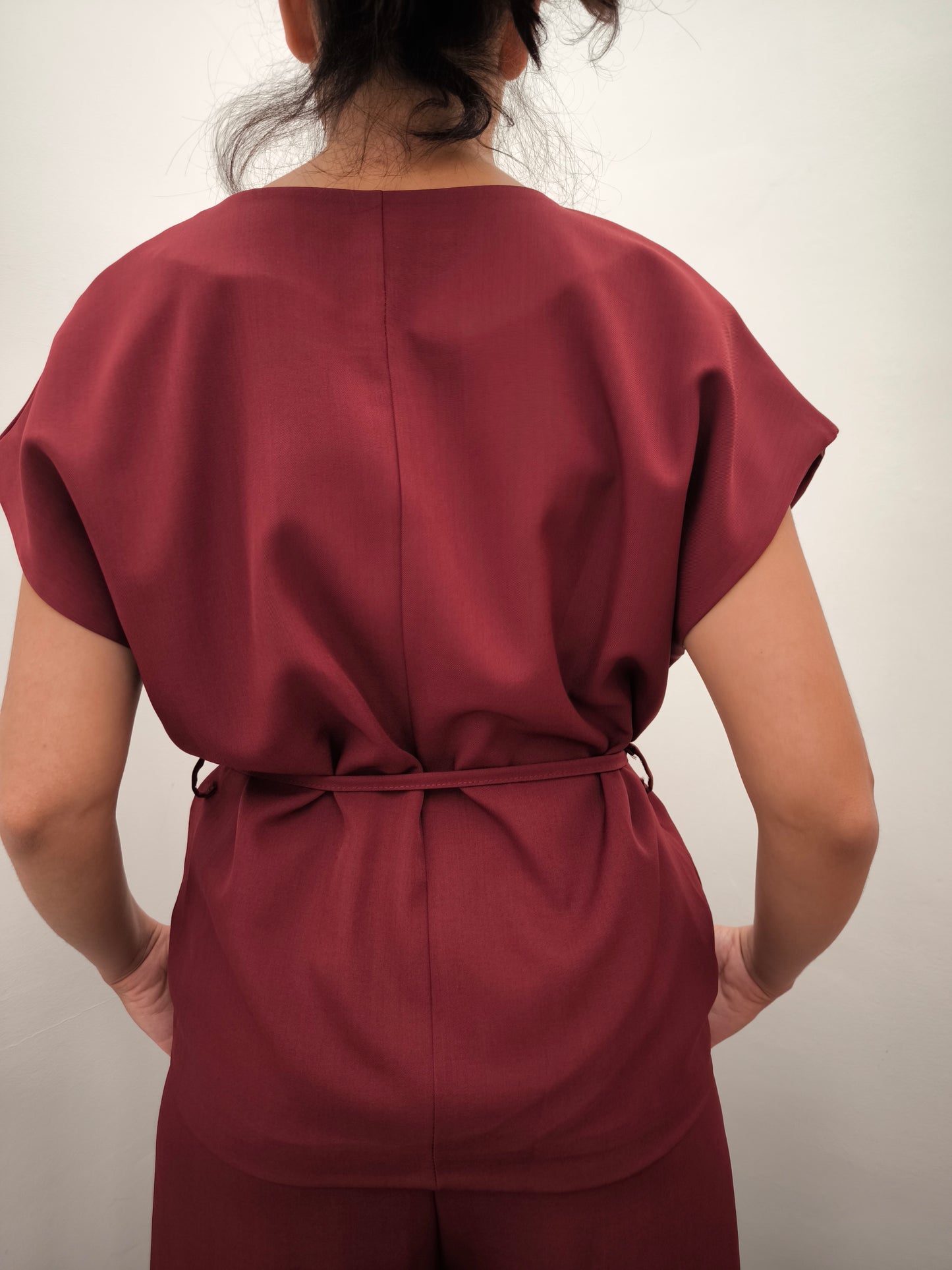 Donna che indossa completo elegante AURA in tessuto bordeaux, con giacca foderata a manica corta