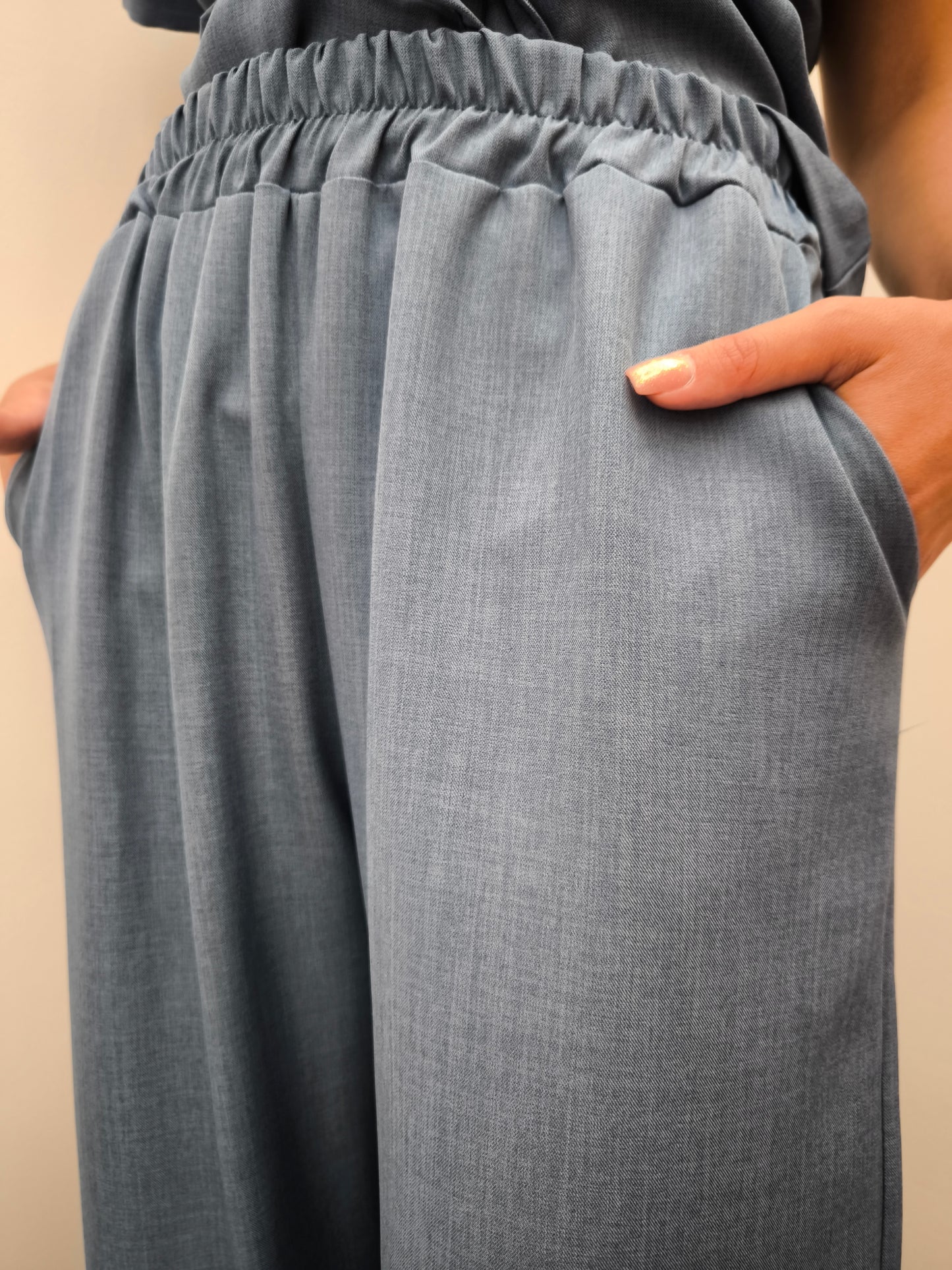 Donna che indossa completo elegante AURA in tessuto denim, con pantaloni larghi.