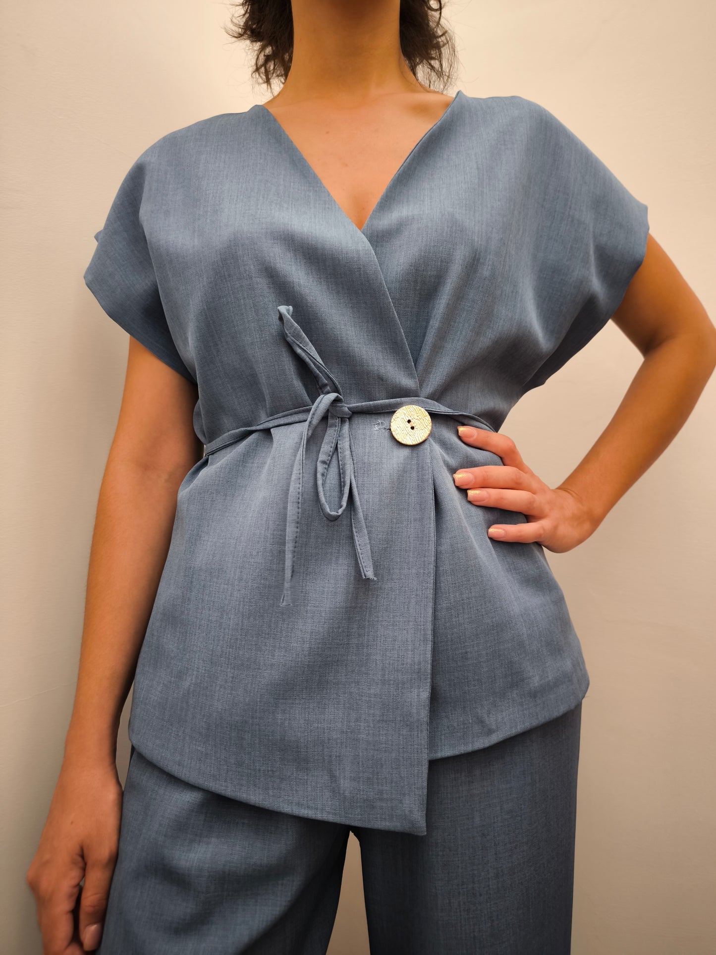 Donna che indossa completo elegante AURA in tessuto denim, con giacca foderata a manica corta
