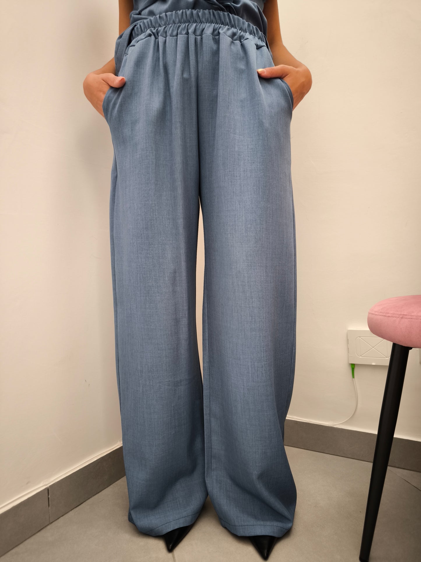 Donna che indossa completo elegante AURA in tessuto denim, con pantaloni larghi.