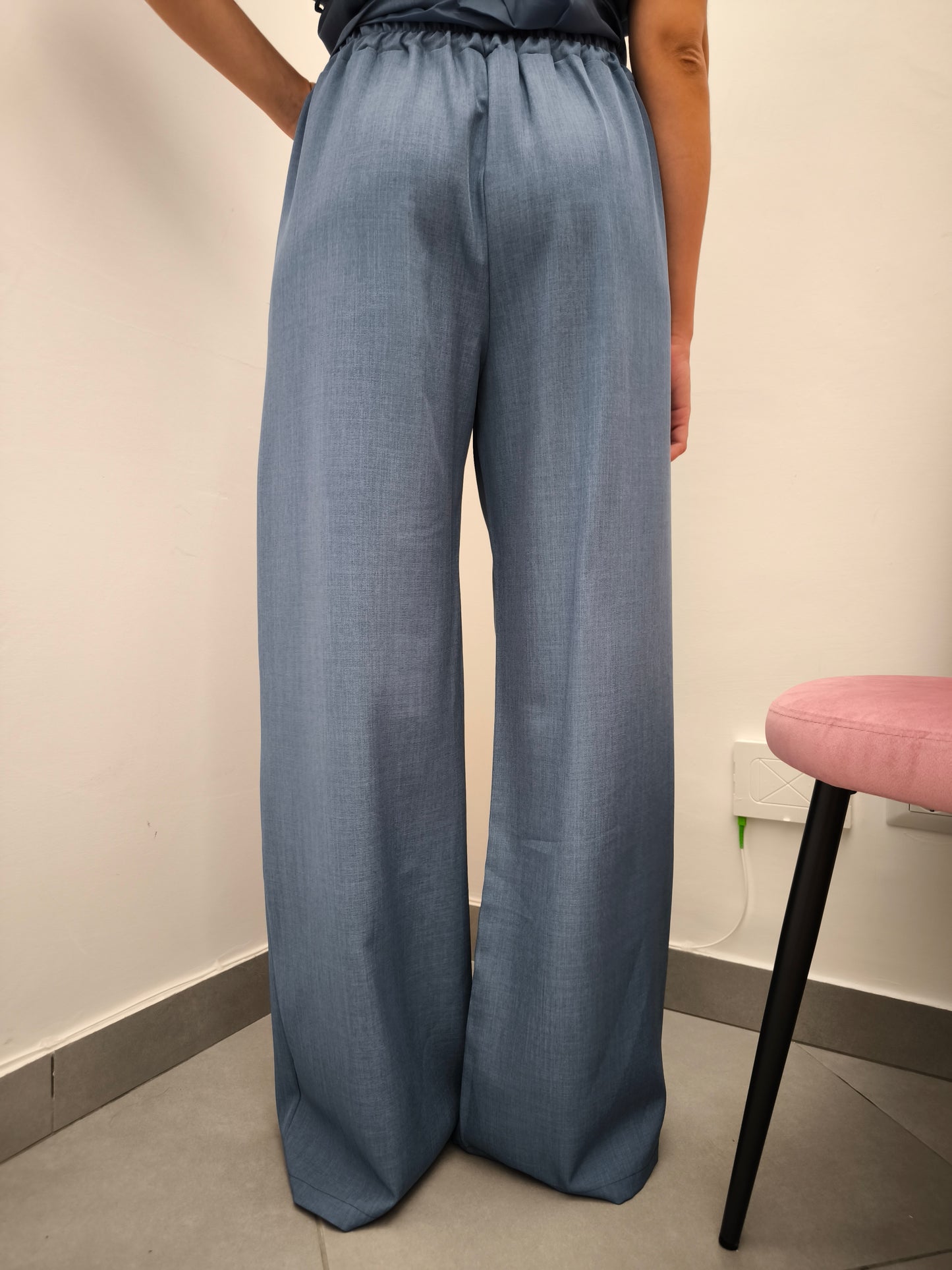 Donna che indossa completo elegante AURA in tessuto denim, con pantaloni larghi.