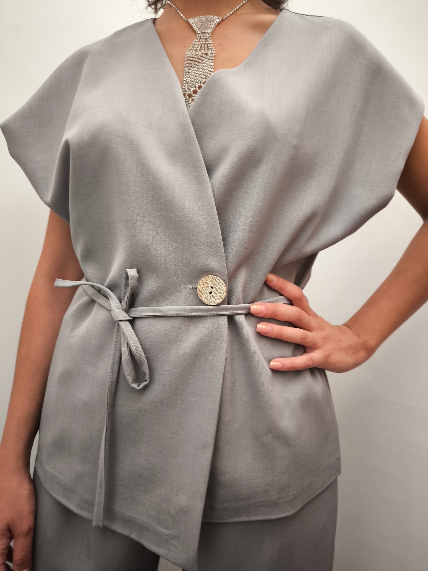 Donna che indossa completo elegante AURA in tessuto grigio, con giacca foderata a manica corta
