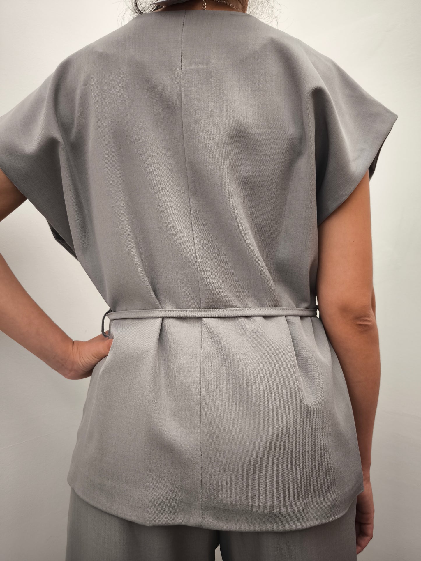 Donna che indossa completo elegante AURA in tessuto grigio, con giacca foderata a manica corta