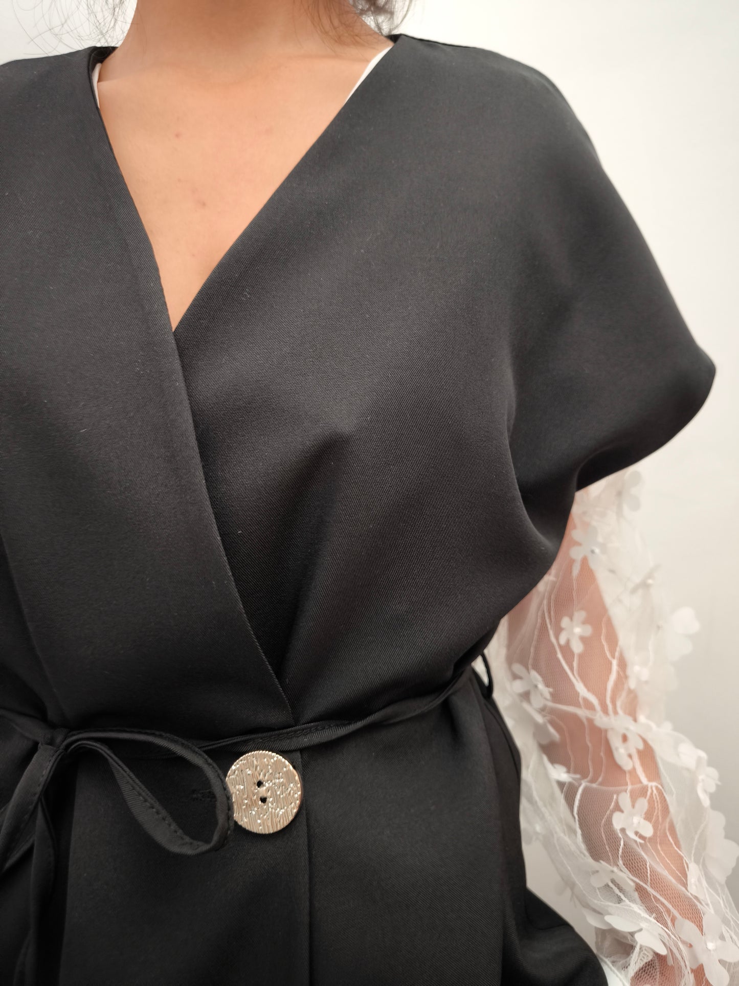 Donna che indossa completo elegante AURA in tessuto nero, con giacca foderata a manica corta