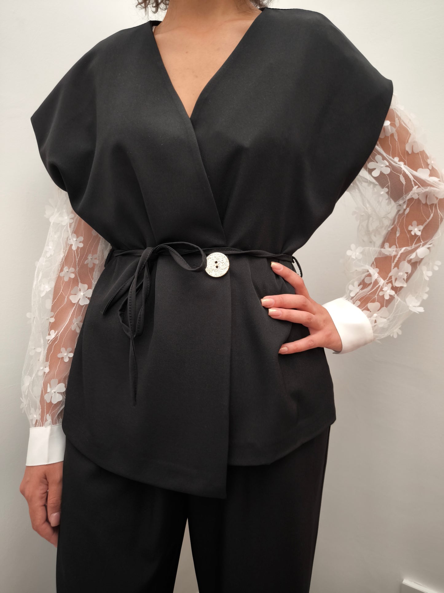 Donna che indossa completo elegante AURA in tessuto nero, con giacca foderata a manica corta