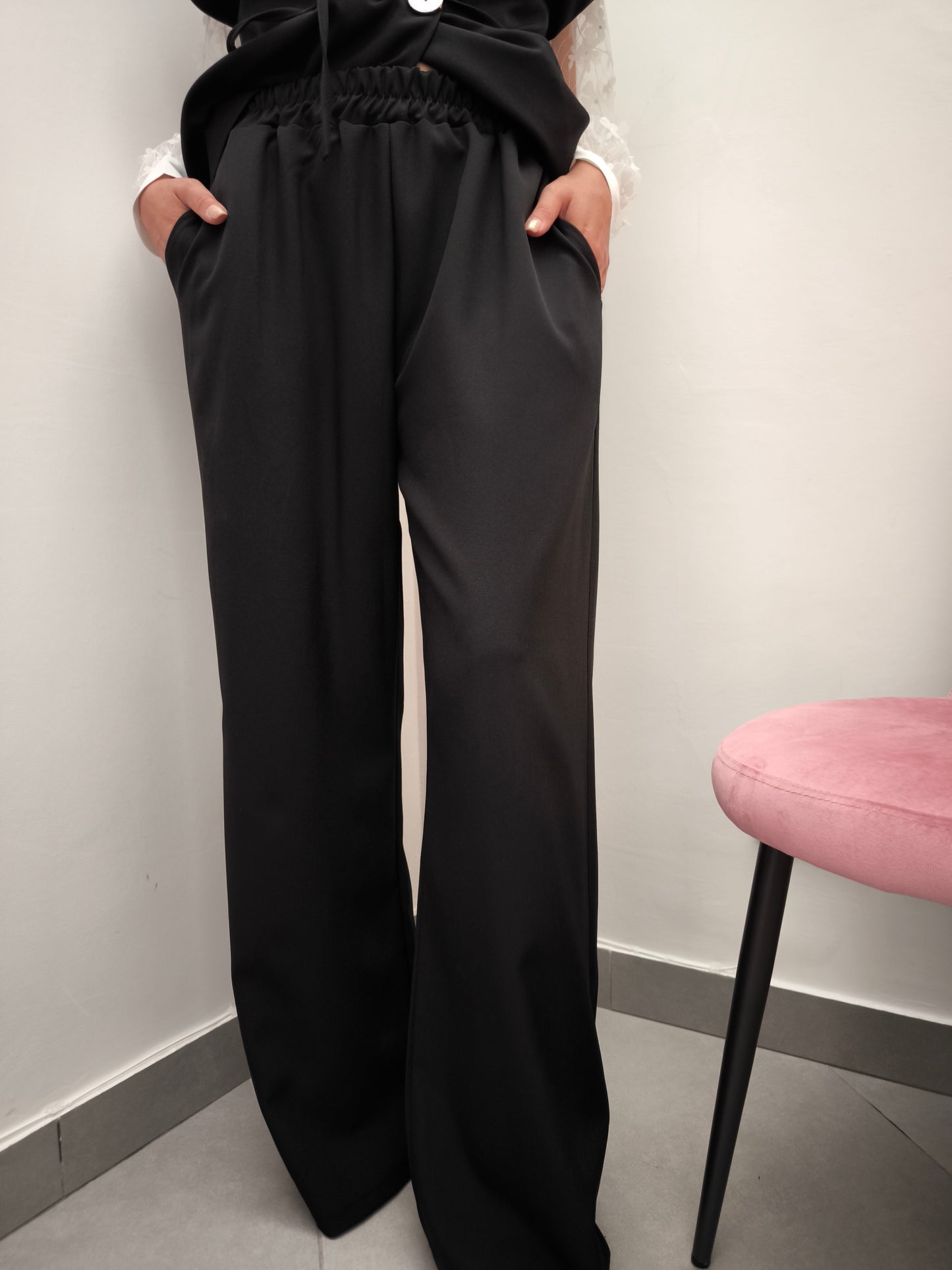 Donna che indossa completo elegante AURA in tessuto nero, con pantaloni larghi.