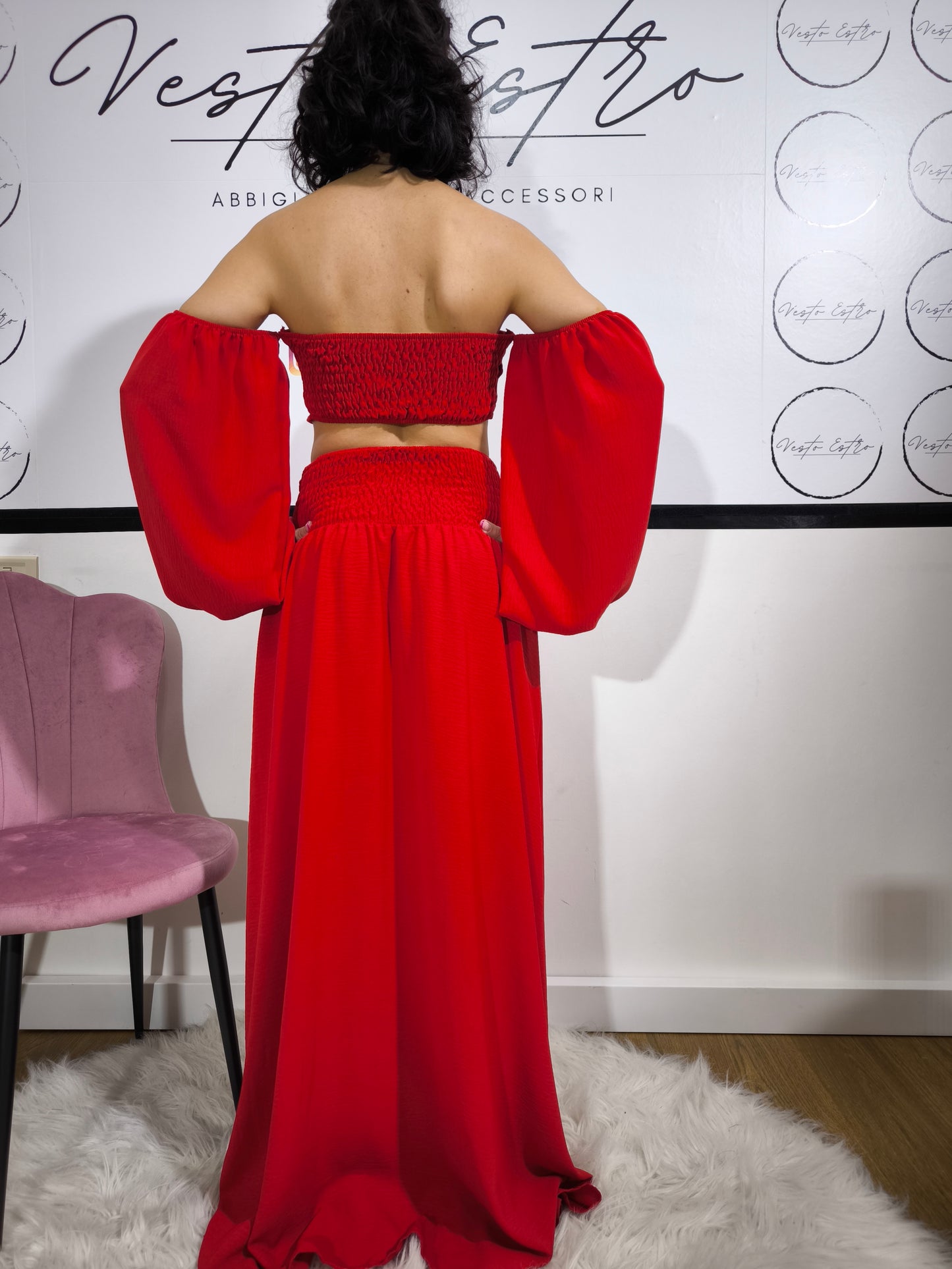Donna indossa un completo rosso con top a fascia con maniche a palloncino e gonna lunga con spacco laterale – outfit elegante Vesto Estro.