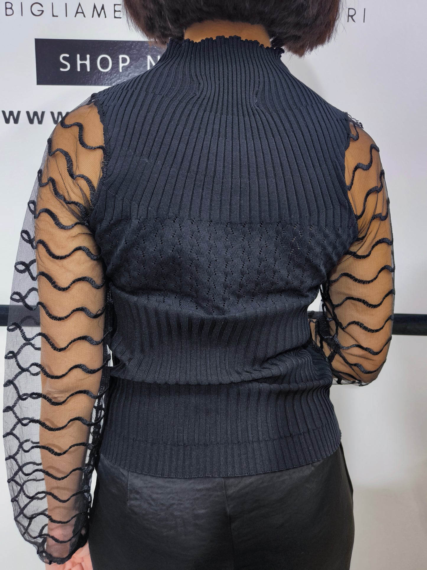 Maglia nera a collo alto con maniche trasparenti in tulle ondulato, abbigliamento elegante donna, perfetto per look casual o formali.