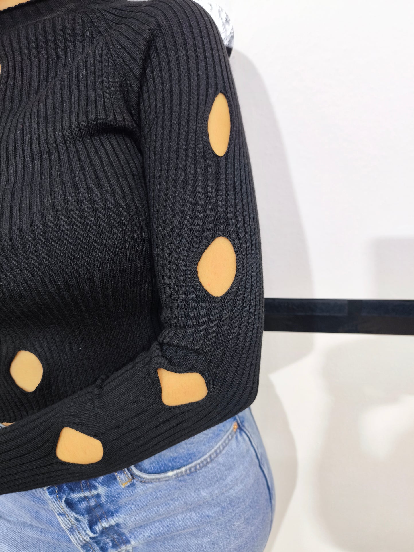 Maglia nera a costine da donna con dettagli cut-out sul davanti.