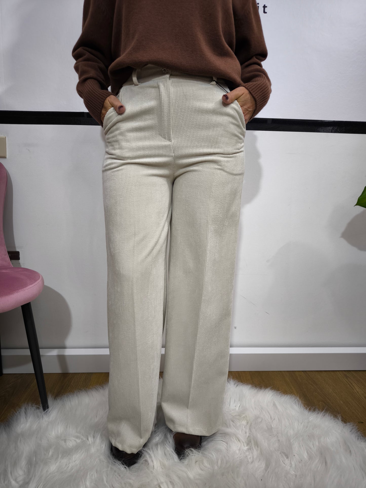 Pantalone in velluto a costine beige con taglio a palazzo indossato da donna con maglione marrone.