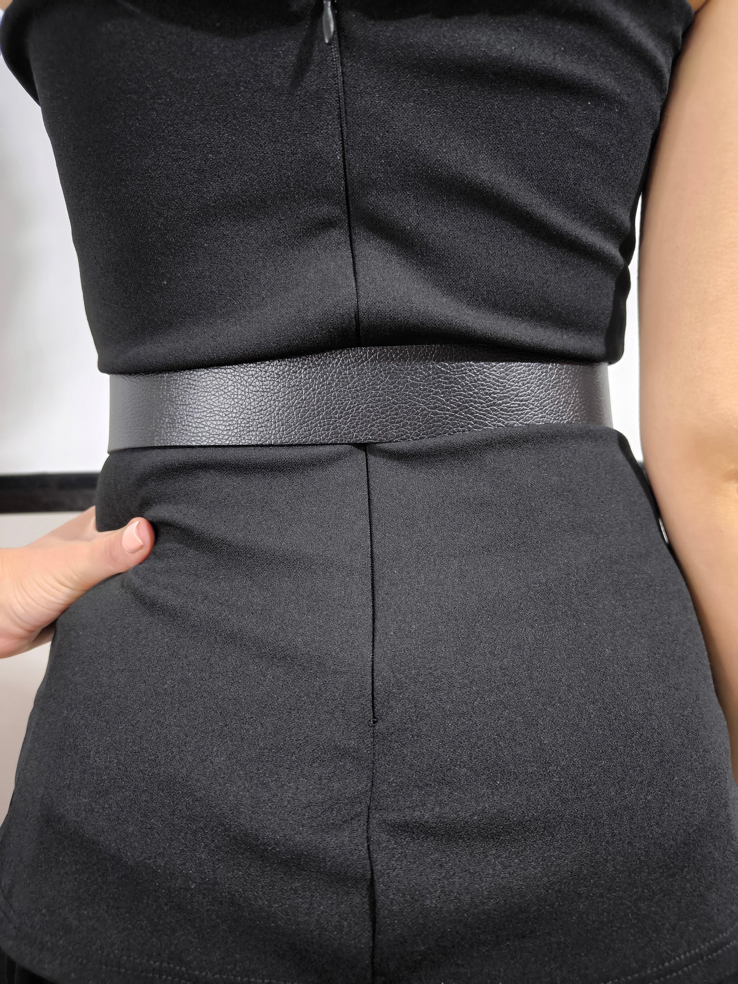 Donna indossa una tutina nera senza spalline con gonnellone in tulle cucito in vita e cintura nera inclusa – look elegante.
