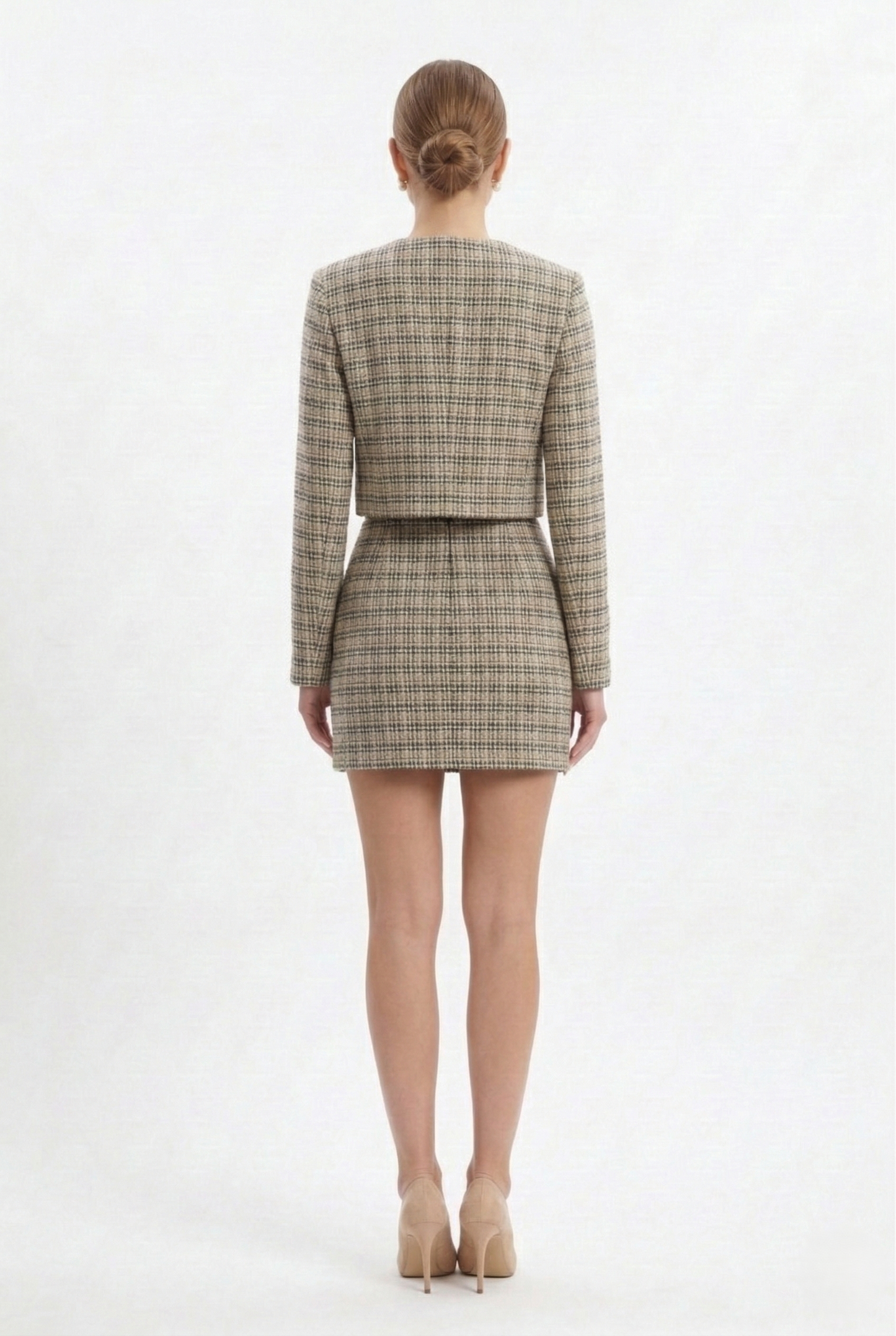 Giacca corta da donna in tweed bianco con bottoni gioiello frontali, parte di completo elegante coordinato.
