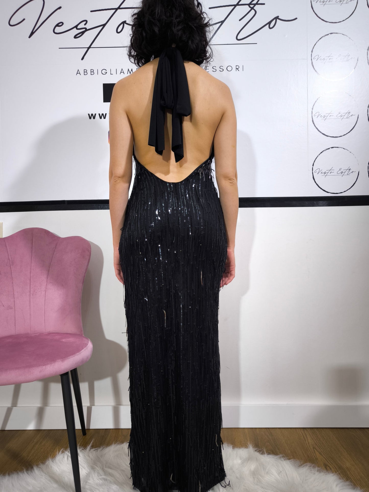 Donna indossa un abito nero lungo stile sirena, con paillettes brillanti e scollo all’americana, perfetto per eventi eleganti – Vesto Estro.