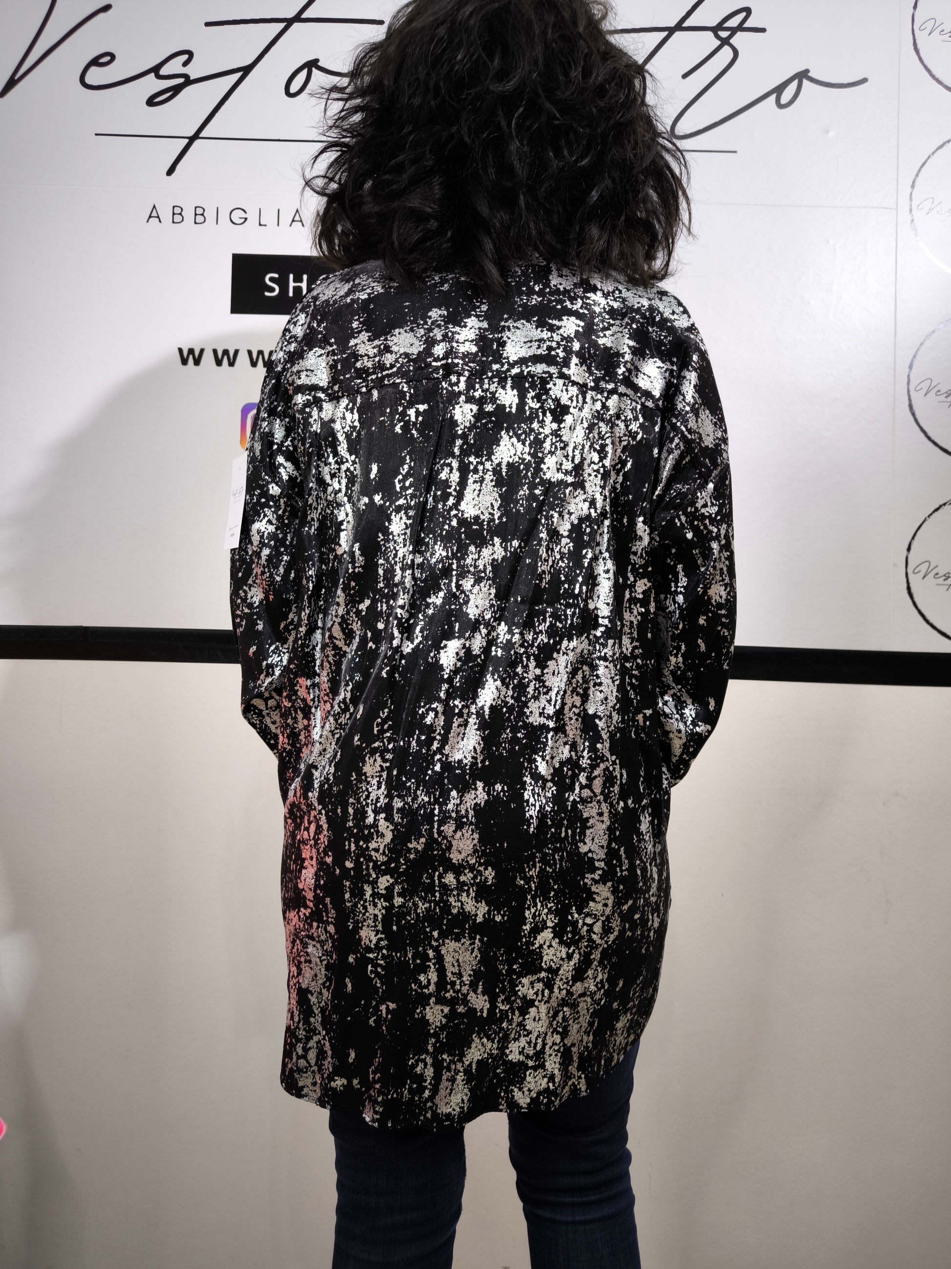Camicia oversize da donna nera con stampa astratta argentata, indossata con jeans. Look moderno ed elegante.