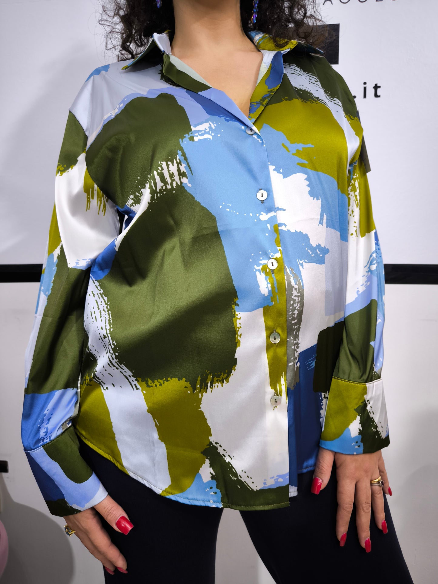 Donna che indossa una camicia satinata a fantasia astratta multicolore con bottoni e colletto classico.