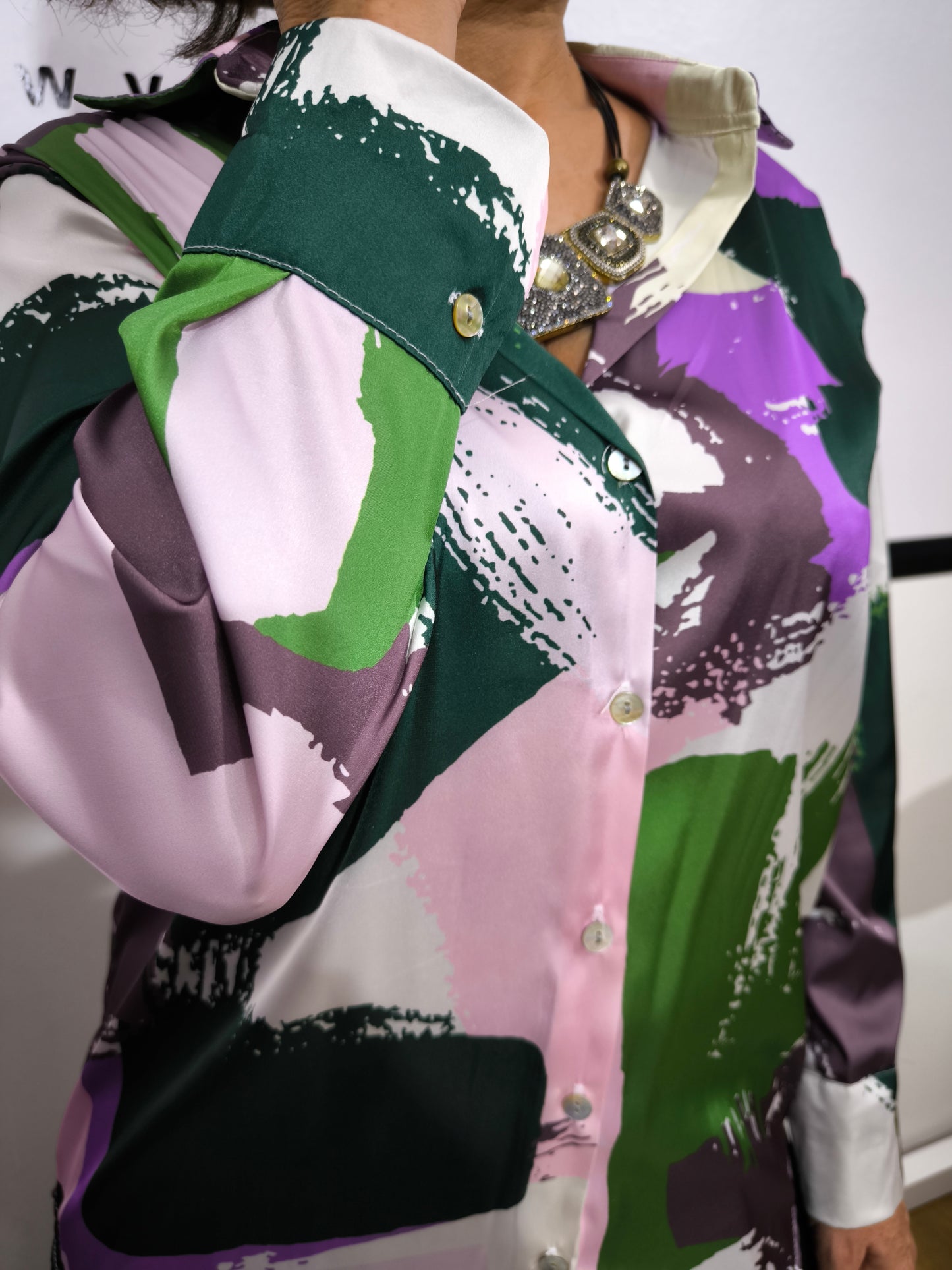 Donna che indossa una camicia satinata a fantasia astratta multicolore con bottoni e colletto classico.