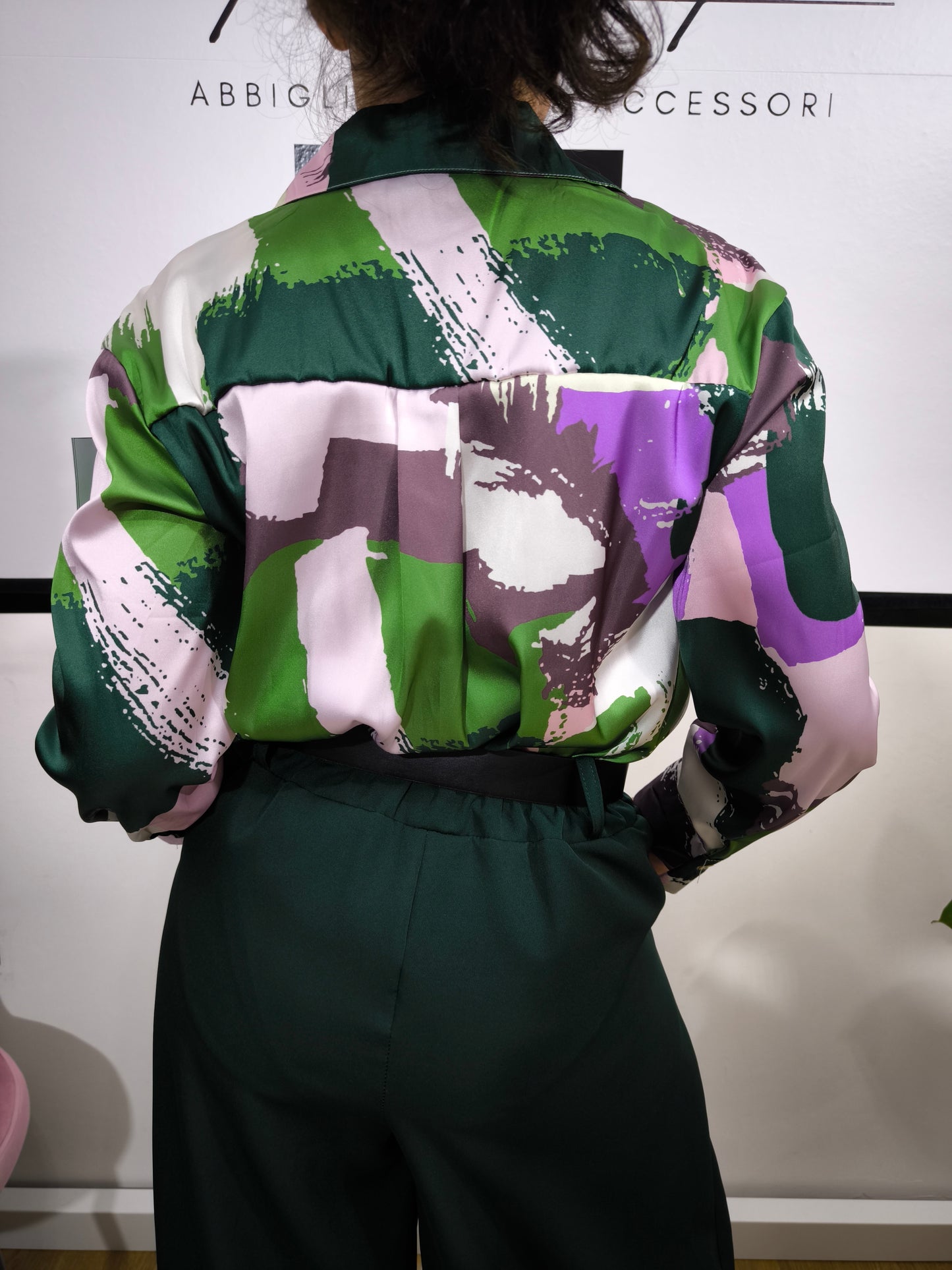 Donna che indossa una camicia satinata a fantasia astratta multicolore con bottoni e colletto classico.