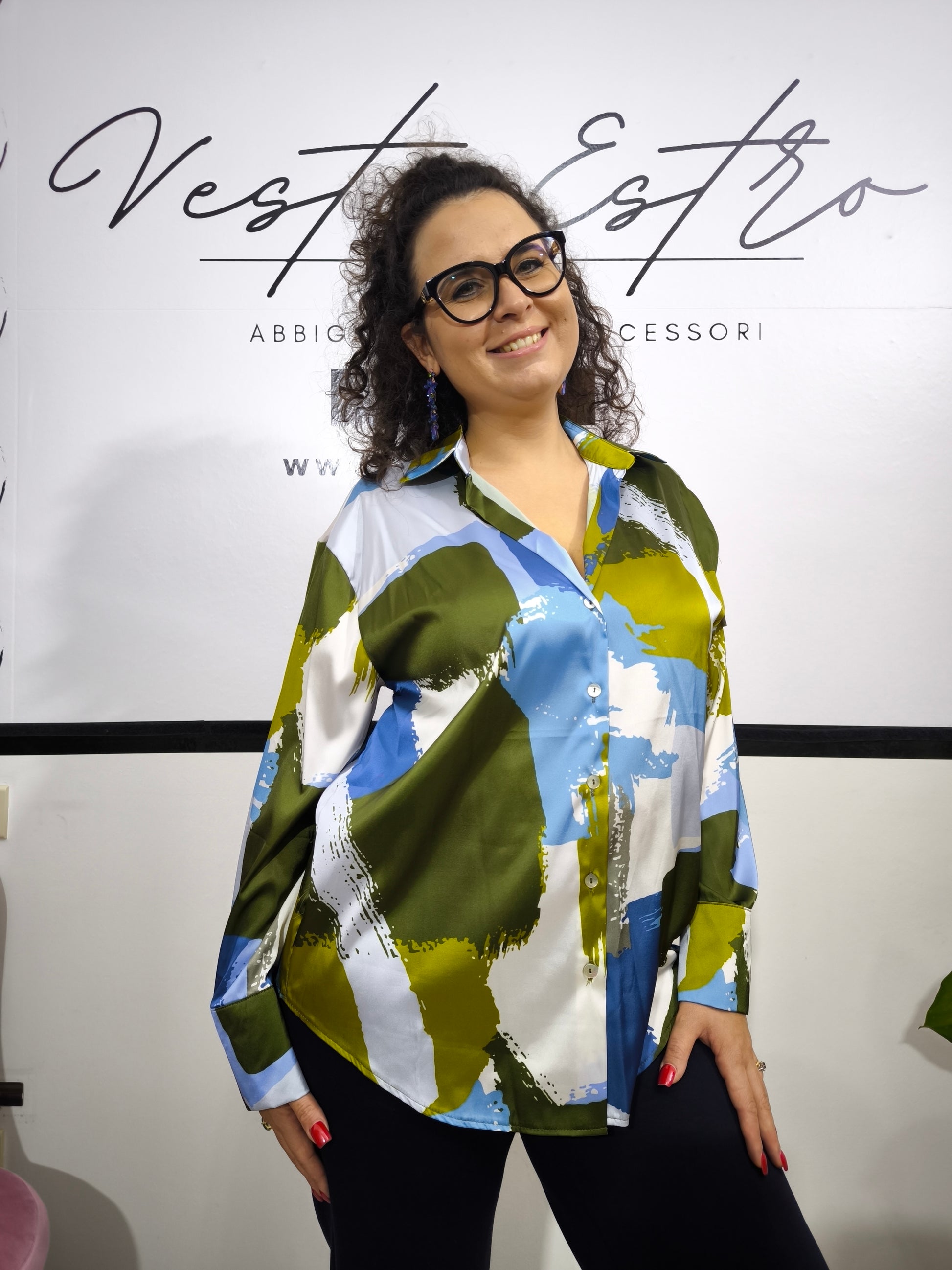 Donna che indossa una camicia satinata a fantasia astratta multicolore con bottoni e colletto classico.