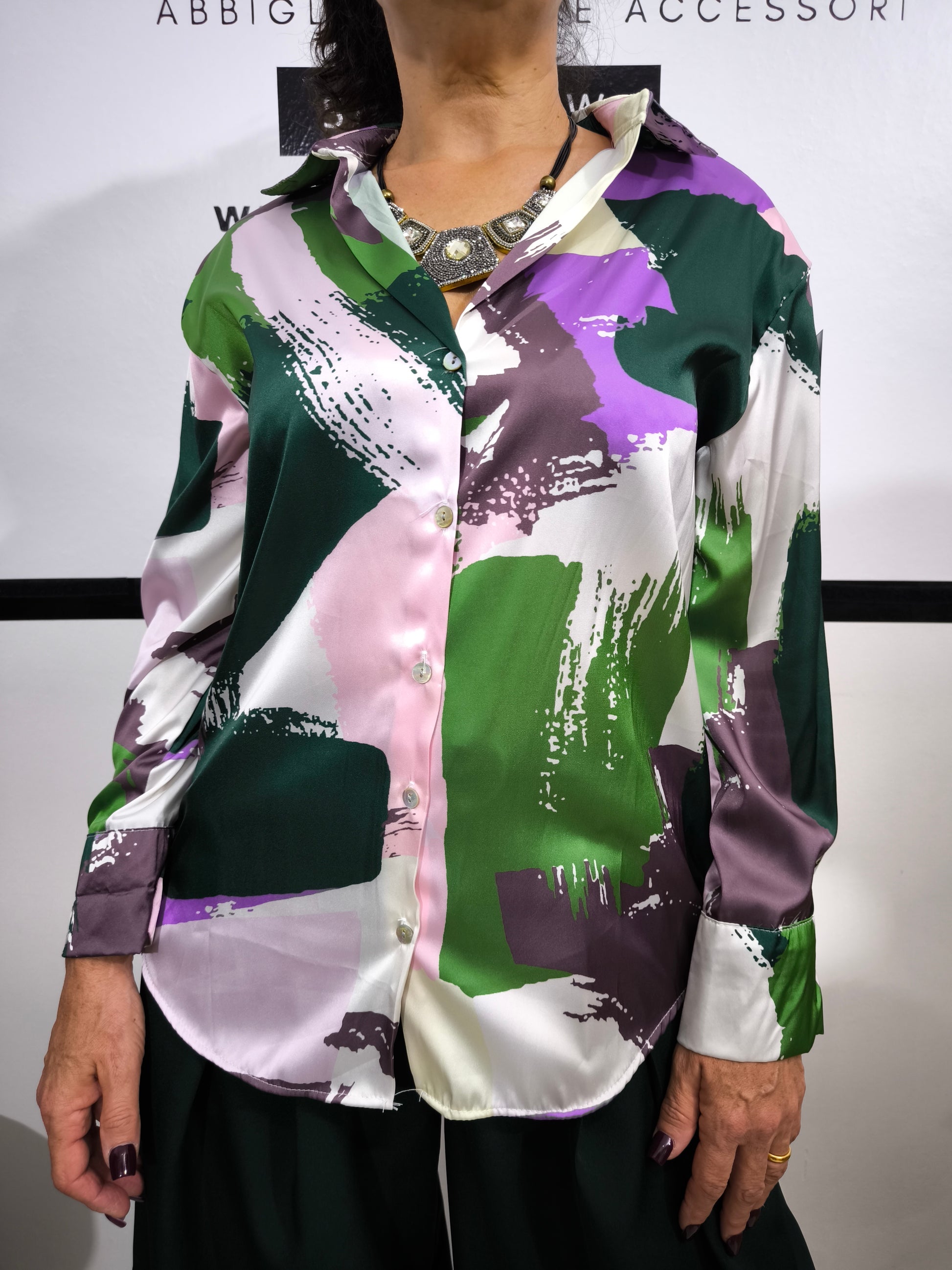 Donna che indossa una camicia satinata a fantasia astratta multicolore con bottoni e colletto classico.
