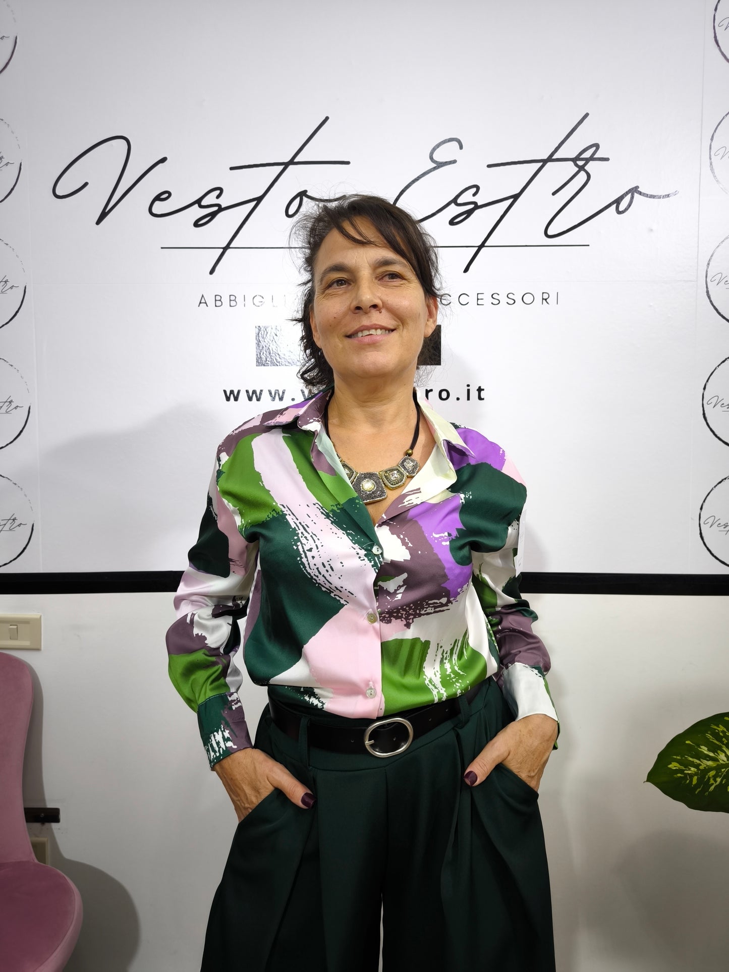 Donna che indossa una camicia satinata a fantasia astratta multicolore con bottoni e colletto classico.