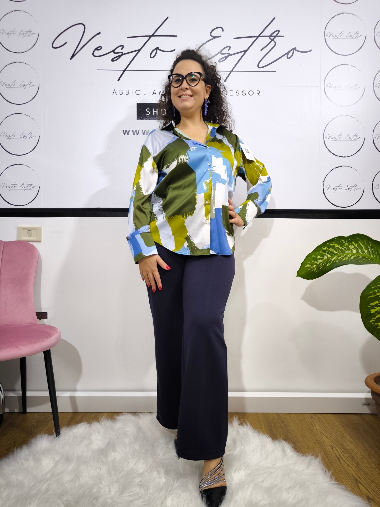 Donna che indossa una camicia satinata a fantasia astratta multicolore con bottoni e colletto classico.