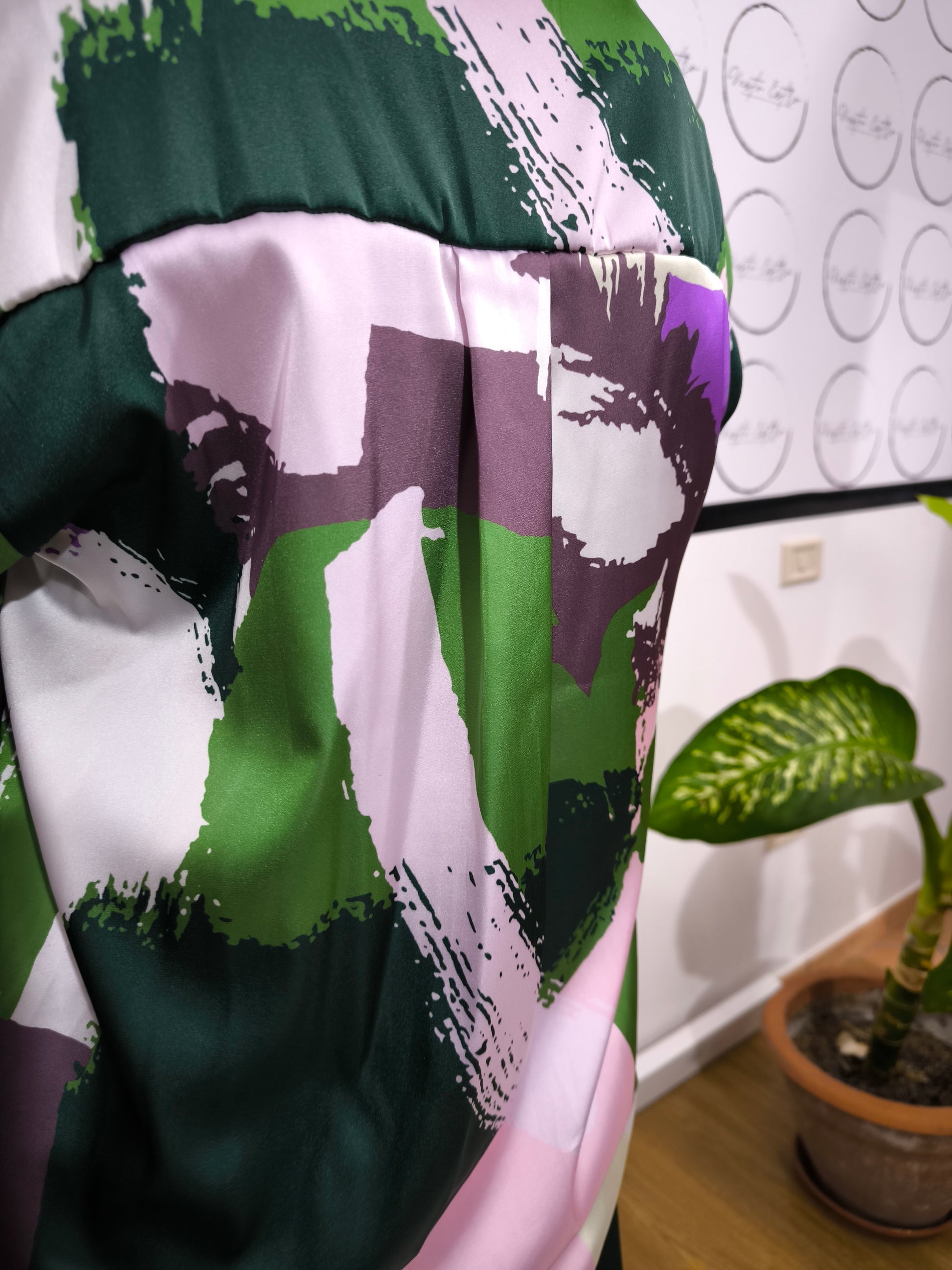 Donna che indossa una camicia satinata a fantasia astratta multicolore con bottoni e colletto classico.