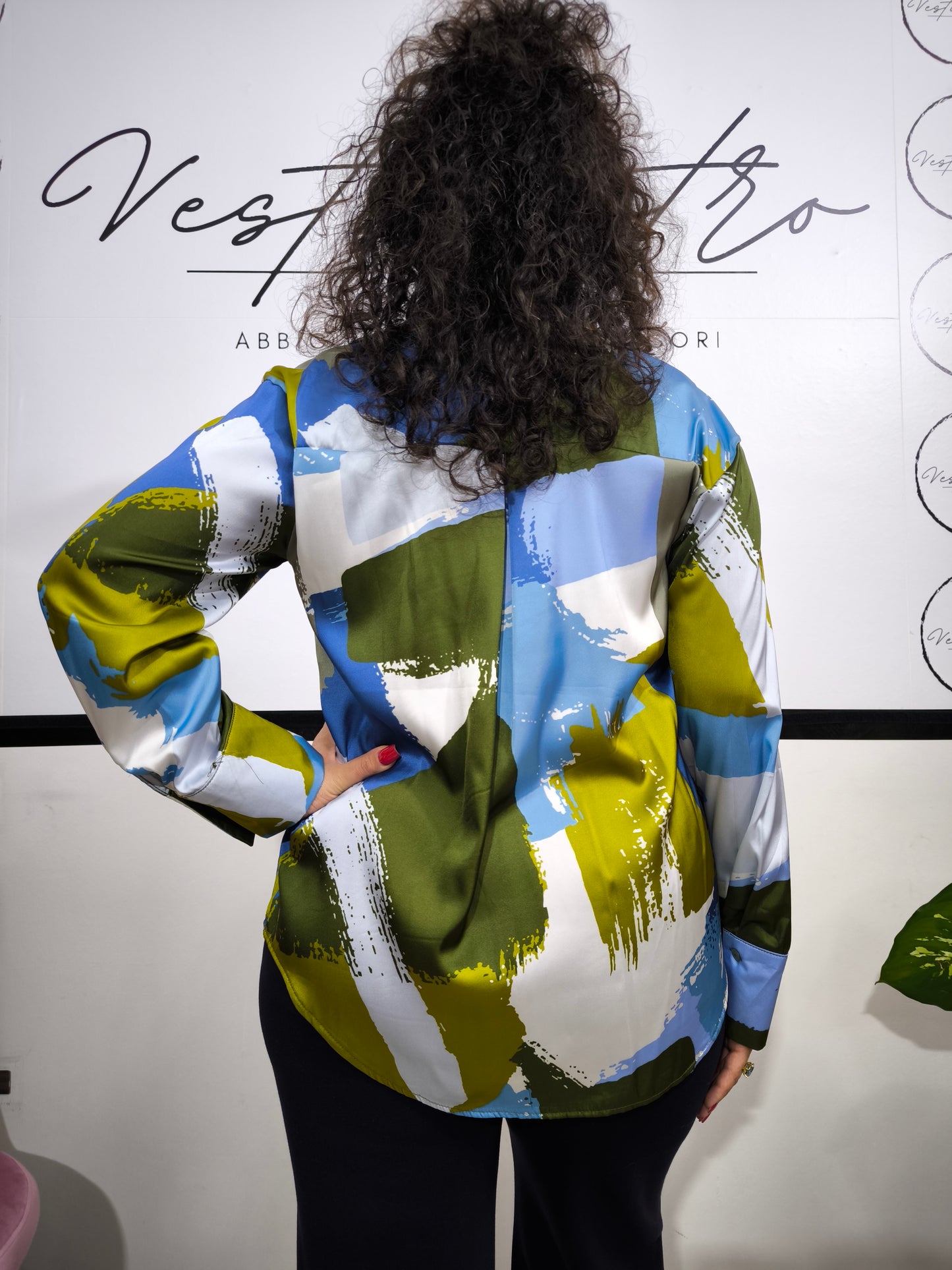 Donna che indossa una camicia satinata a fantasia astratta multicolore con bottoni e colletto classico.