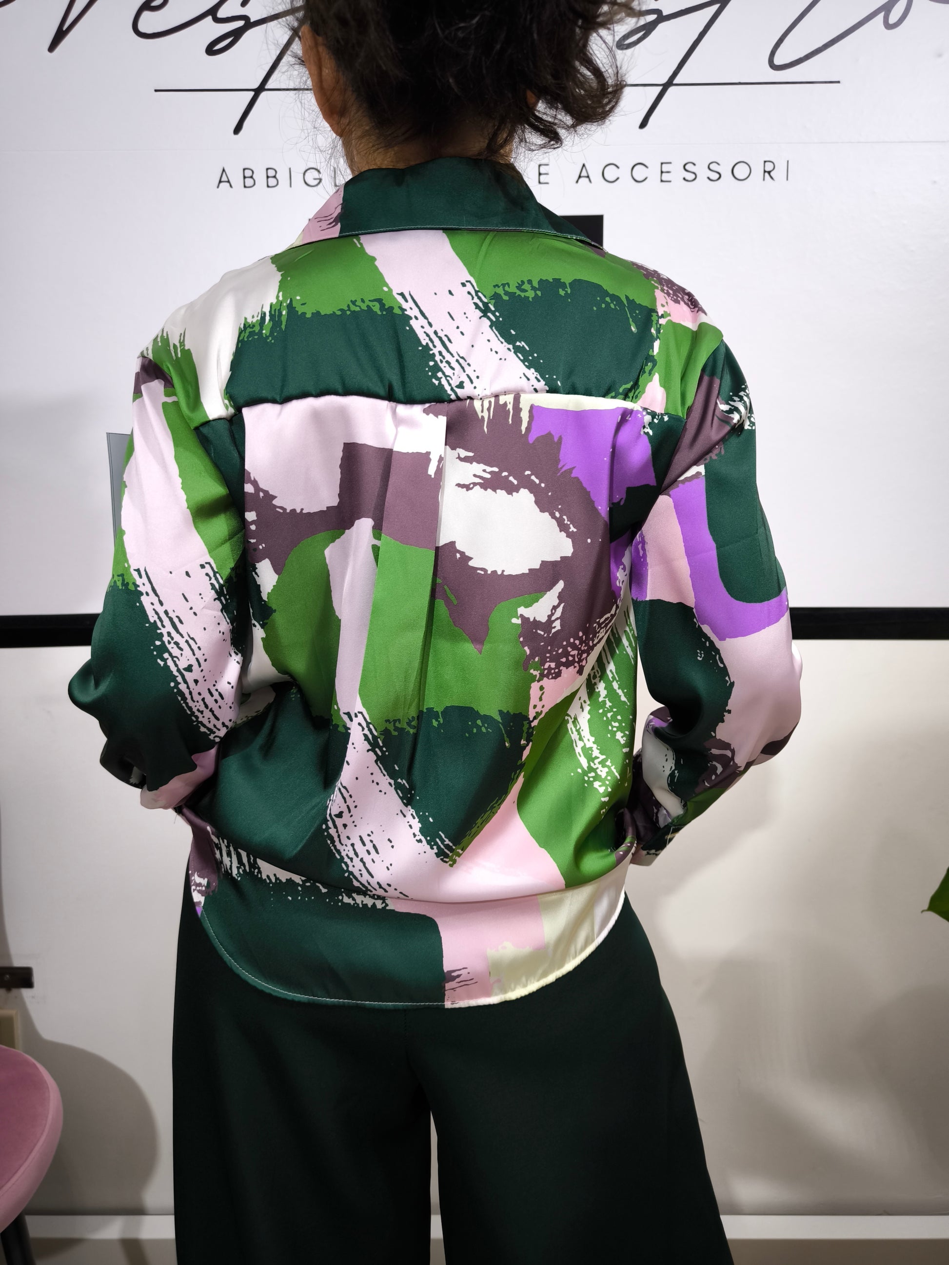 Donna che indossa una camicia satinata a fantasia astratta multicolore con bottoni e colletto classico.