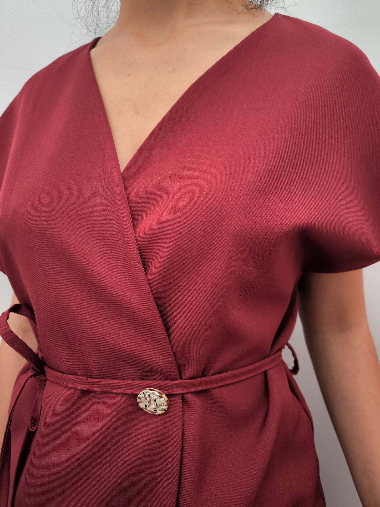 Donna che indossa completo elegante AURA in tessuto bordeaux, con giacca foderata a manica corta