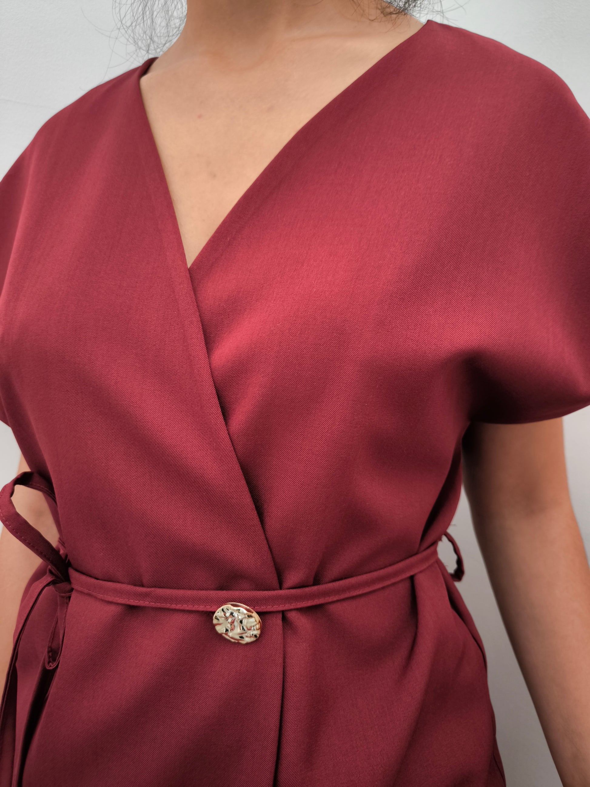 Donna che indossa completo elegante AURA in tessuto bordeaux, con giacca foderata a manica corta