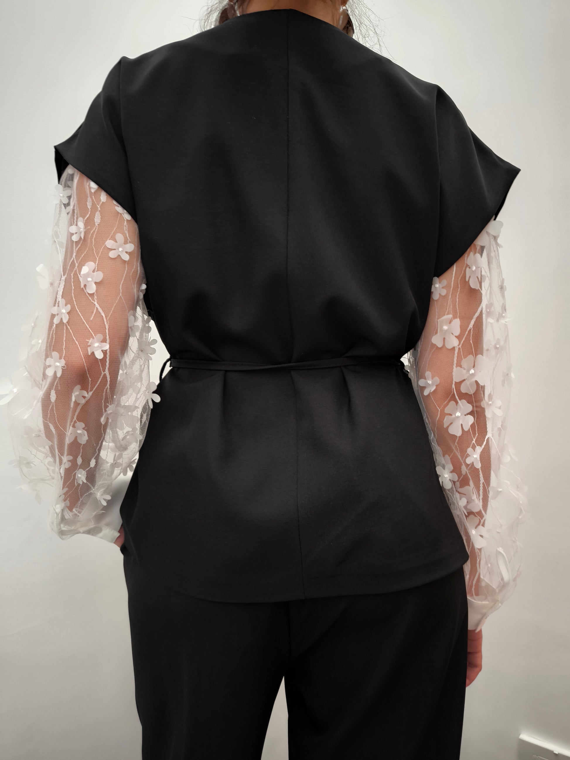 Donna che indossa completo elegante AURA in tessuto nero, con giacca foderata a manica corta