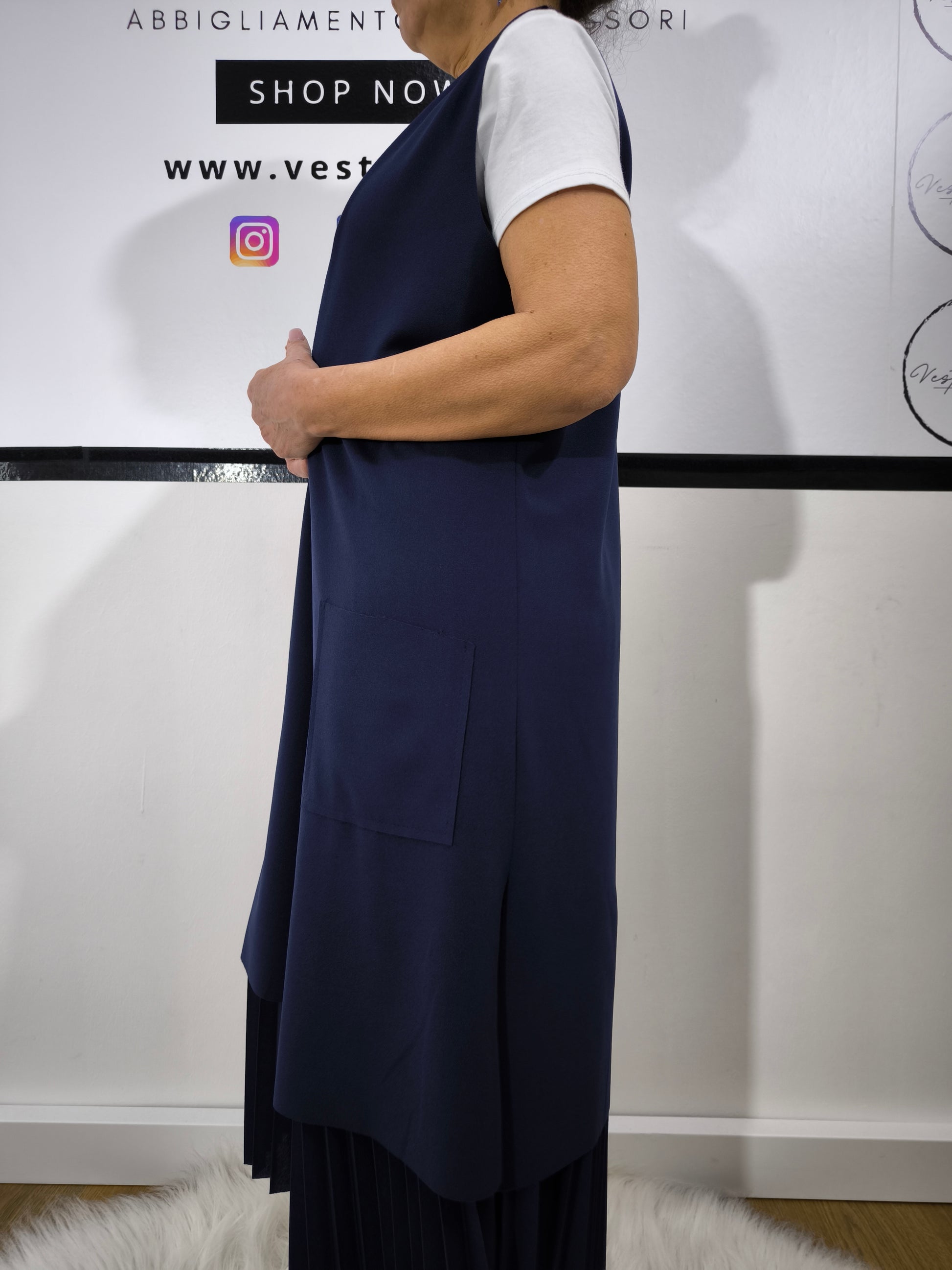 Completo donna con gilet lungo blu e t-shirt bianca, abbinato a gonna plissettata, perfetto per un look casual elegante.