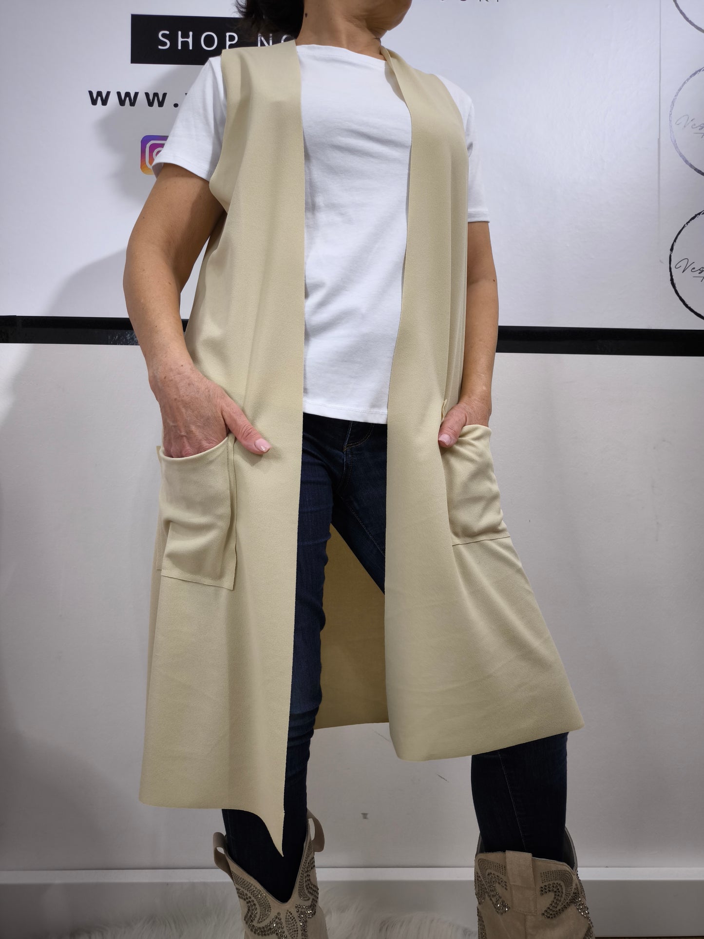 Completo donna con gilet lungo crema e t-shirt bianca, abbinato a jeans, perfetto per un look casual elegante.