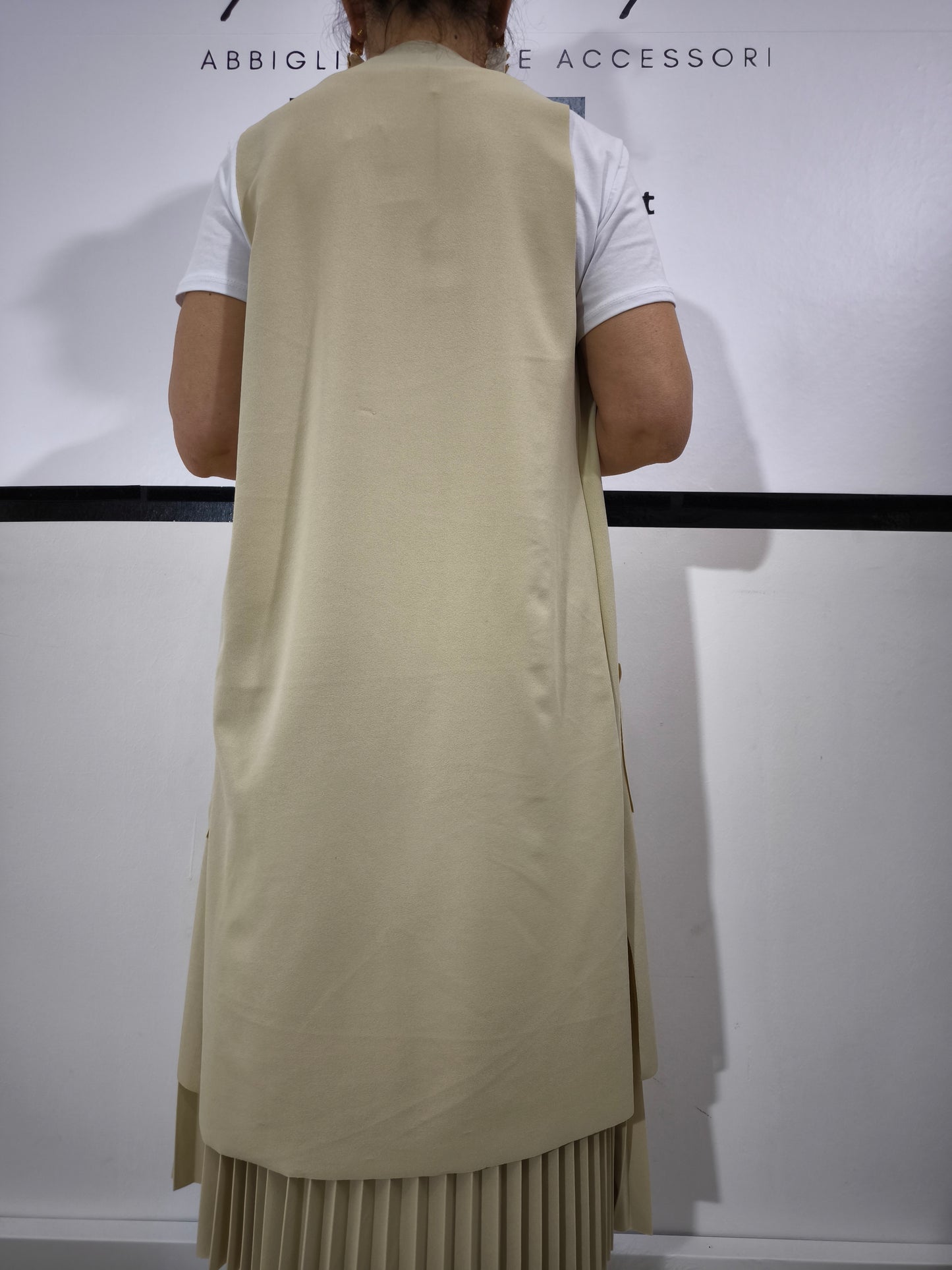 Completo donna con gilet lungo crema e t-shirt bianca, abbinato a gonna plissettata, perfetto per un look casual elegante.