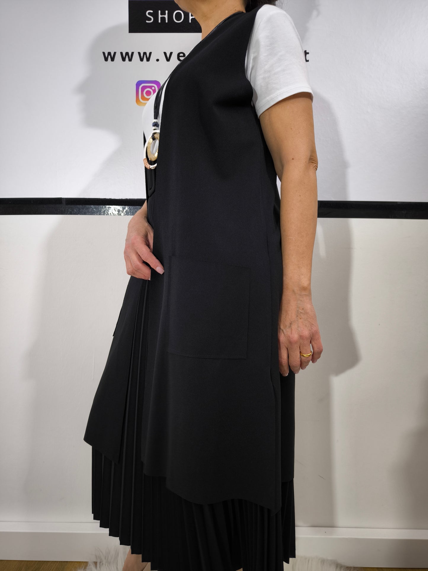 Completo donna con gilet lungo nero e t-shirt bianca, abbinato a gonna plissettata, perfetto per un look casual elegante.