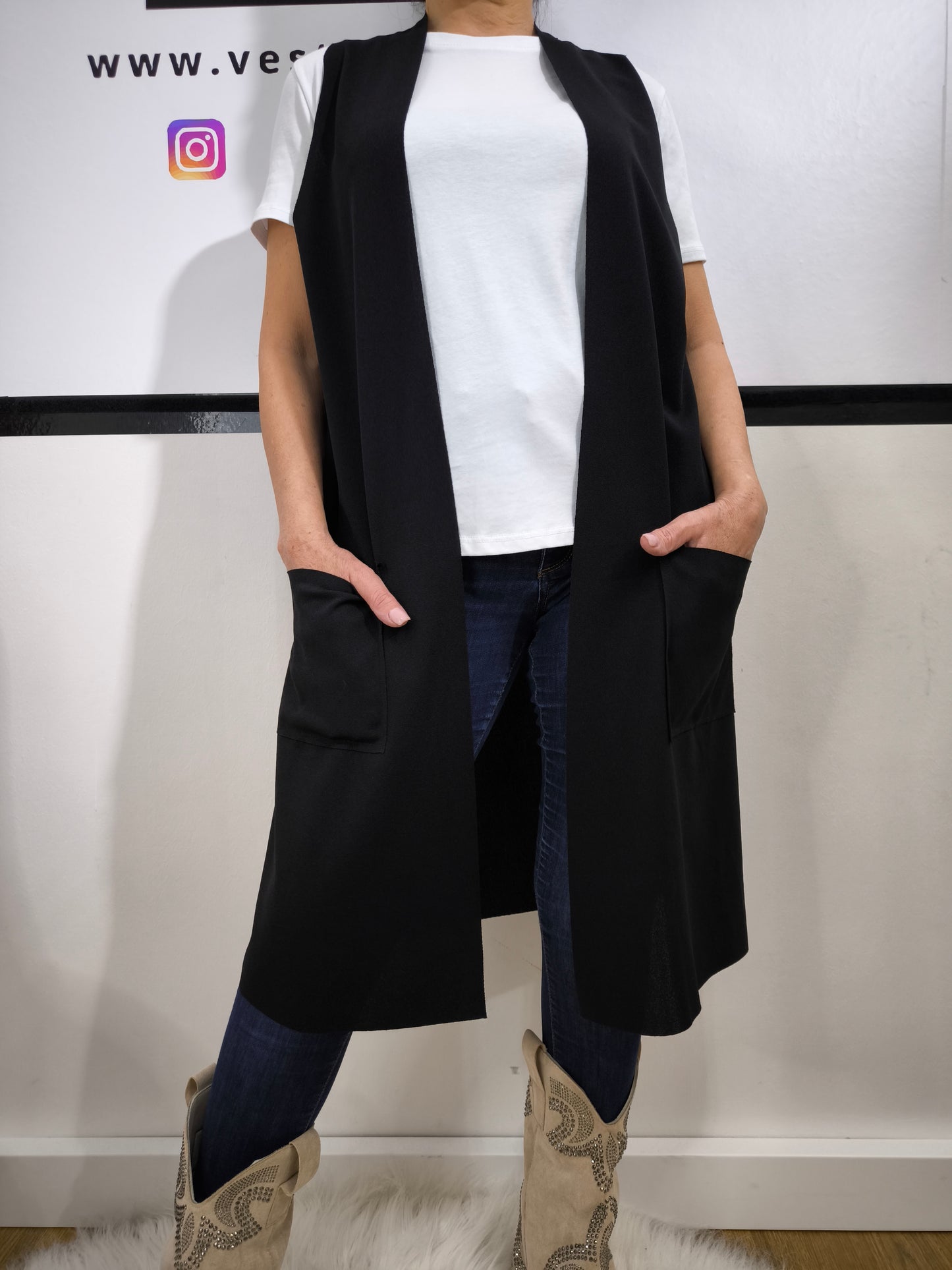 Completo donna con gilet lungo nero e t-shirt bianca, abbinato a jeans, perfetto per un look casual elegante.