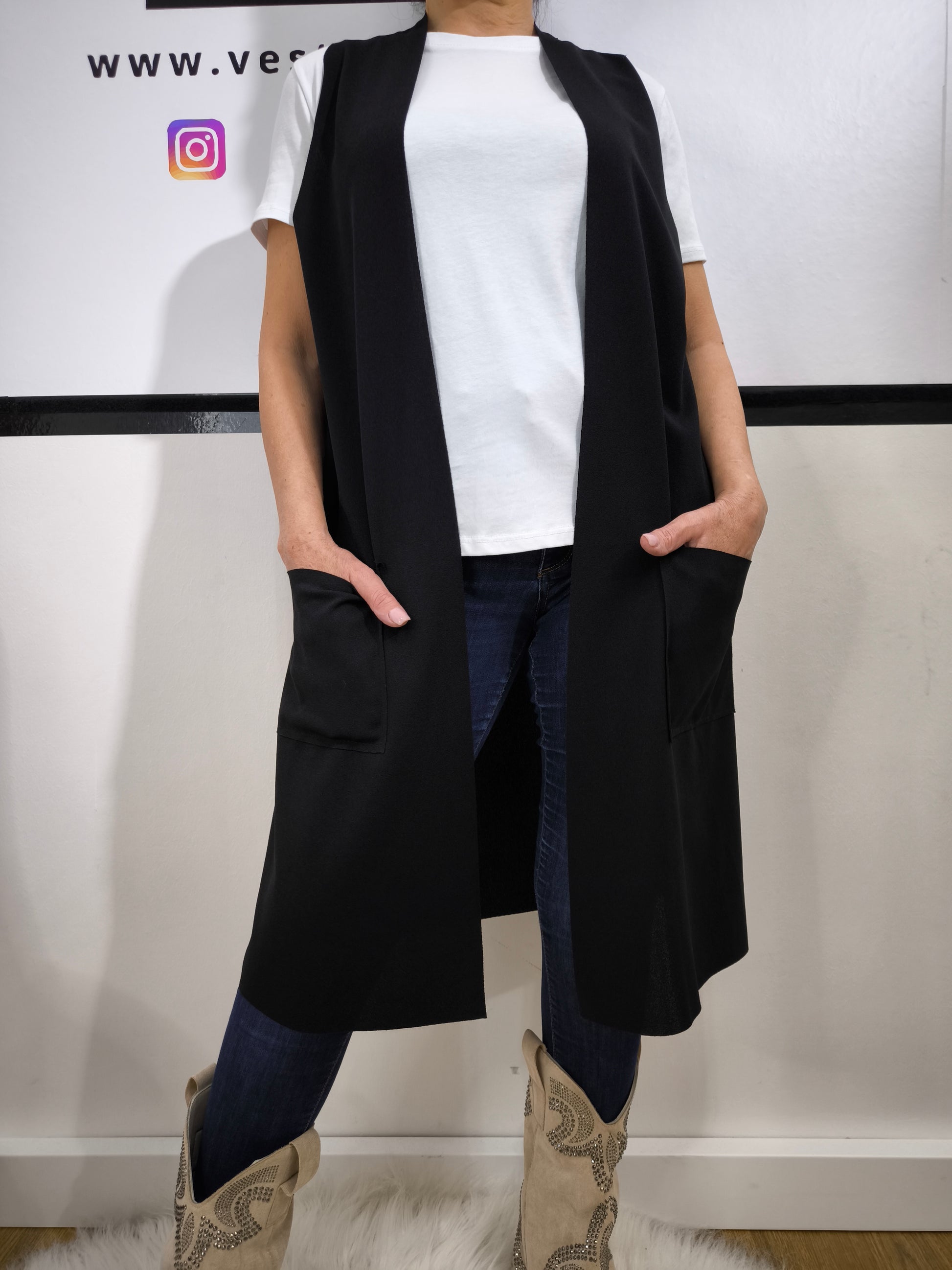 Completo donna con gilet lungo nero e t-shirt bianca, abbinato a jeans, perfetto per un look casual elegante.