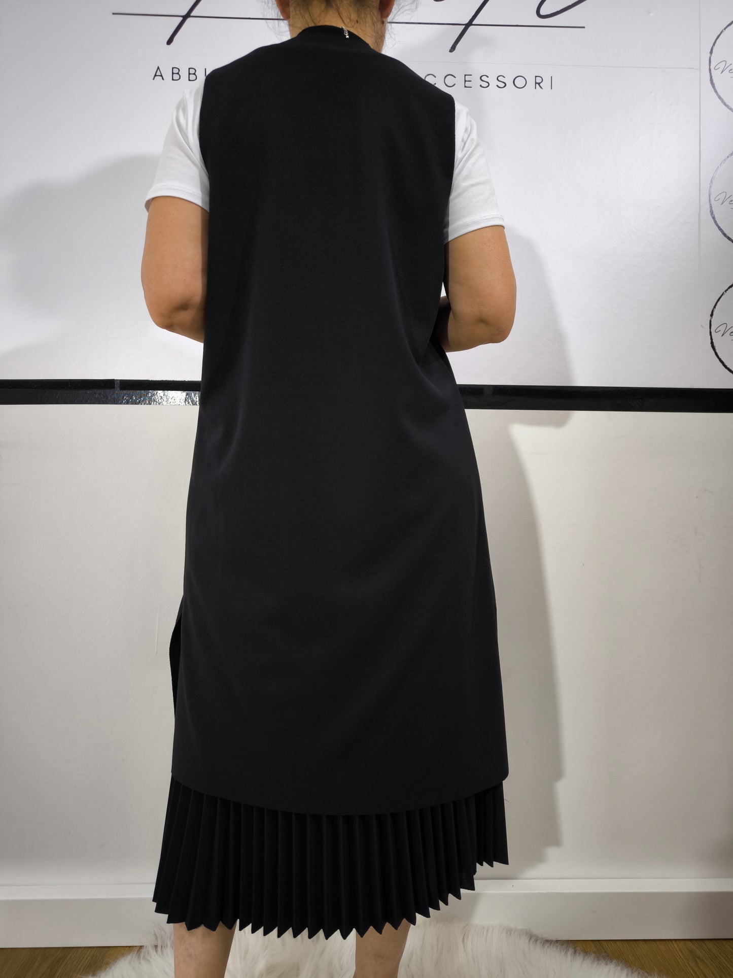 Completo donna con gilet lungo nero e t-shirt bianca, abbinato a gonna plissettata, perfetto per un look casual elegante.