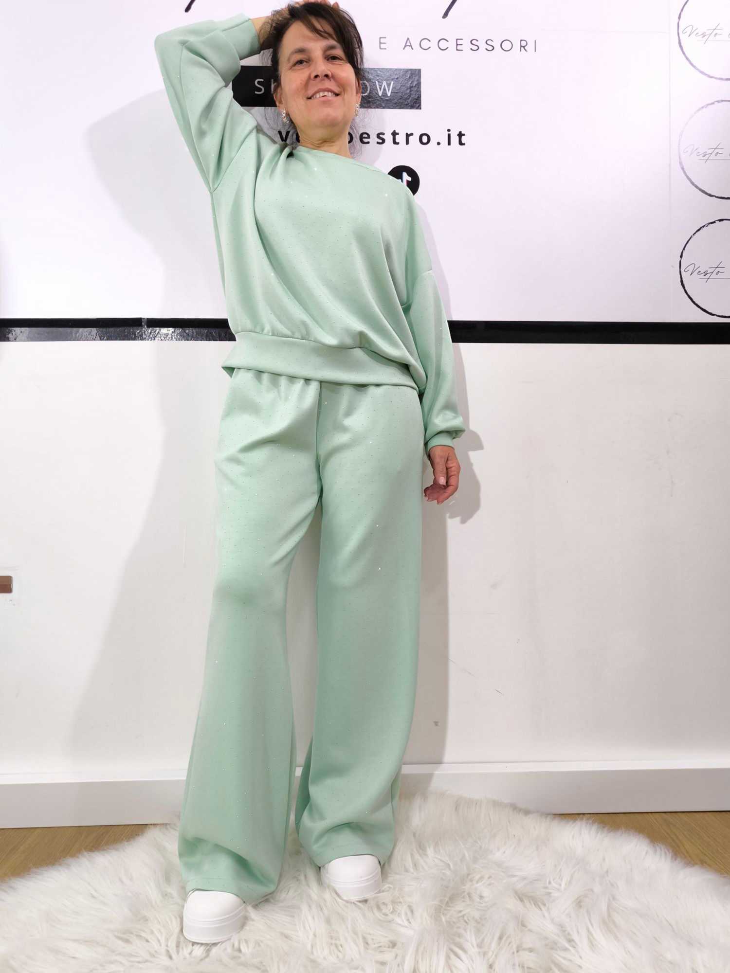 Completo donna in felpa verde menta con strass, composto da felpa oversize e pantaloni larghi, indossato con sneakers bianche.