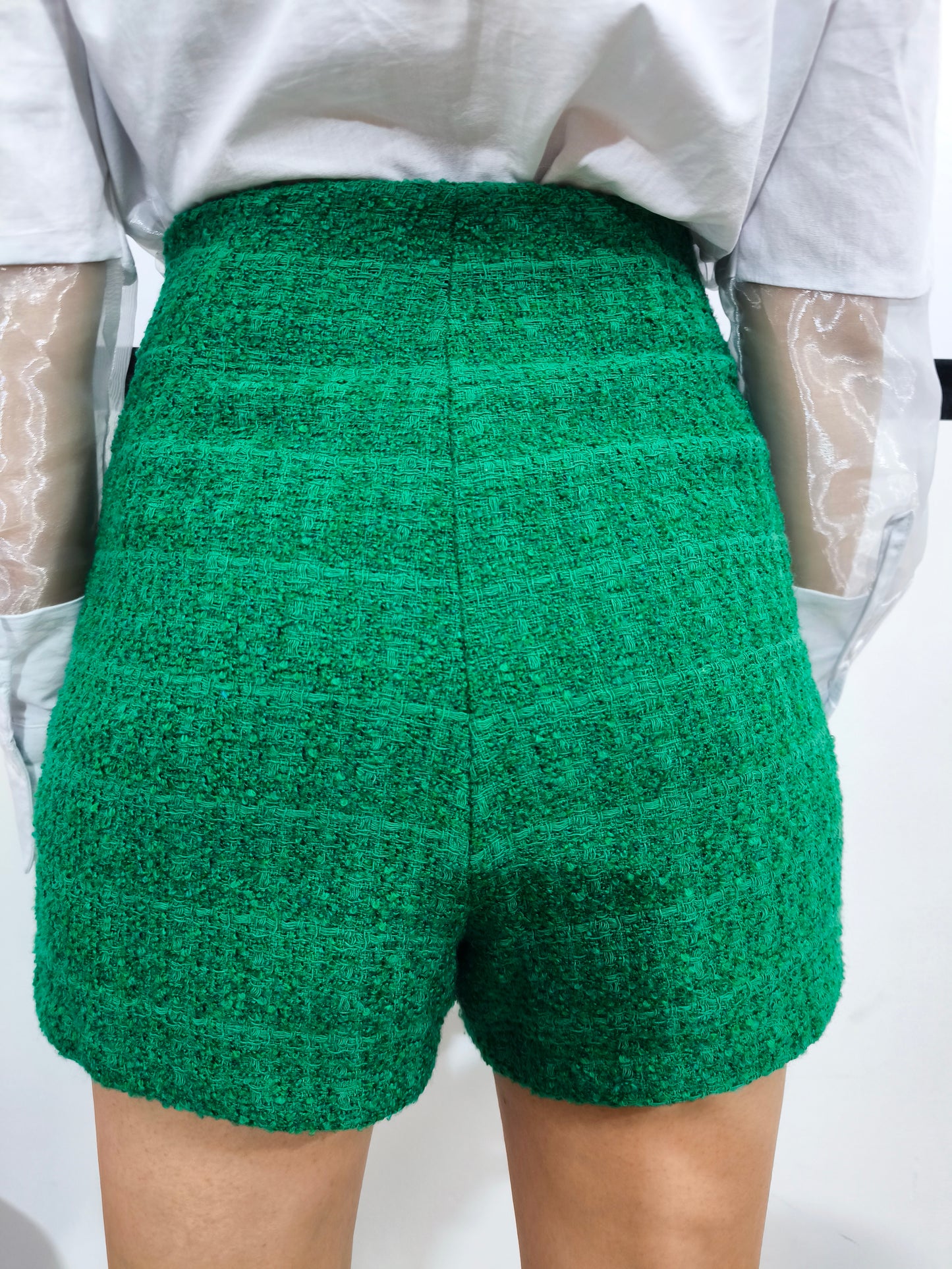 Gonna pantaloncino corta in tessuto tweed verde con dettaglio a bottoni e design avvolgente, perfetta per un look casual chic ed elegante.