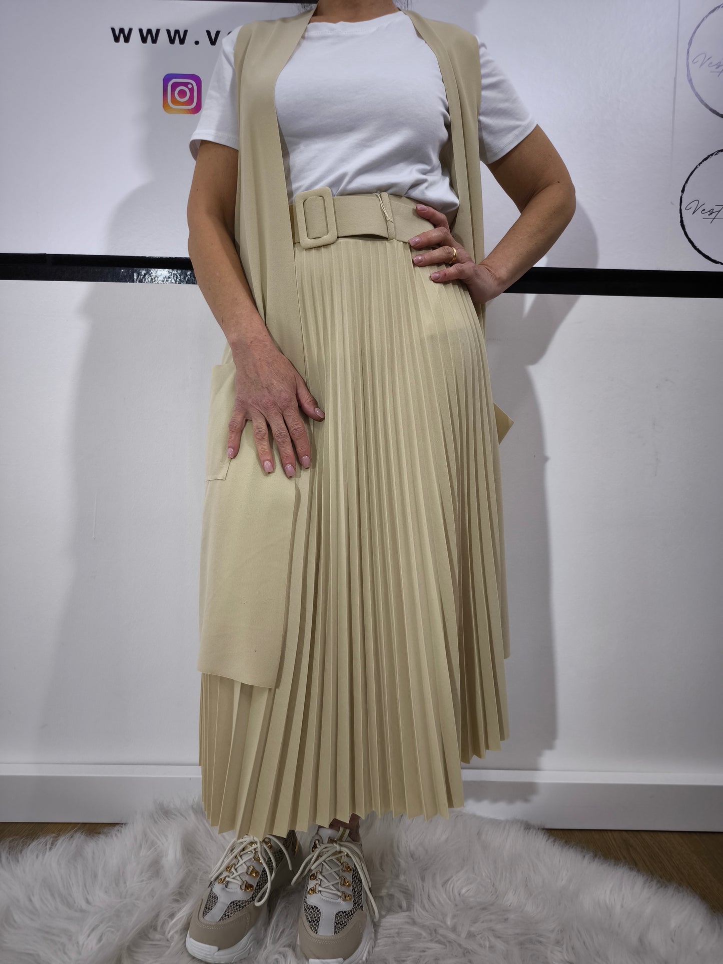 Gonna plissettata crema midi con cintura, abbinata a una t-shirt bianca, per un look elegante e moderno.