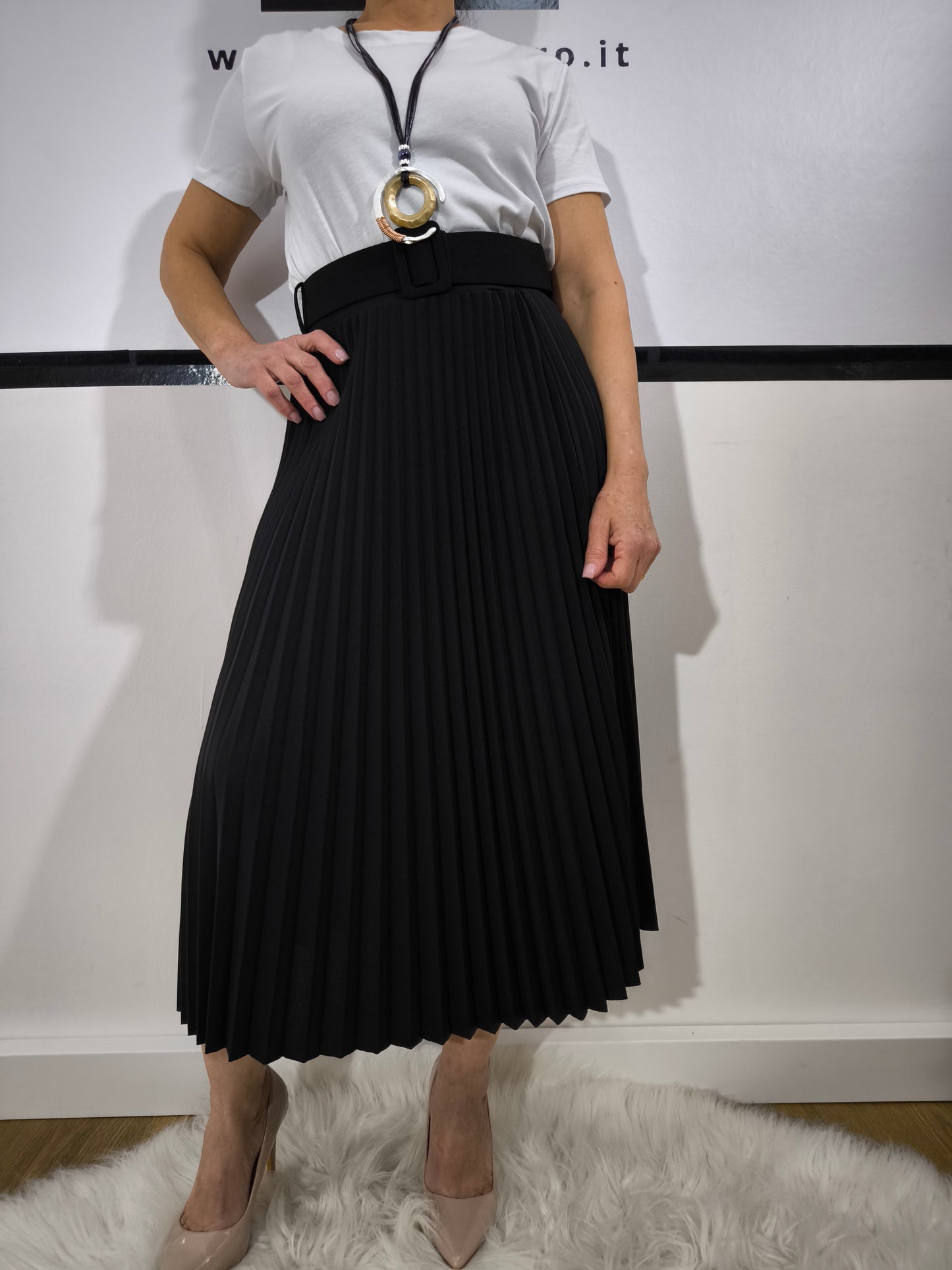 Gonna plissettata nera midi con cintura, abbinata a una t-shirt bianca e collana, per un look elegante e moderno.