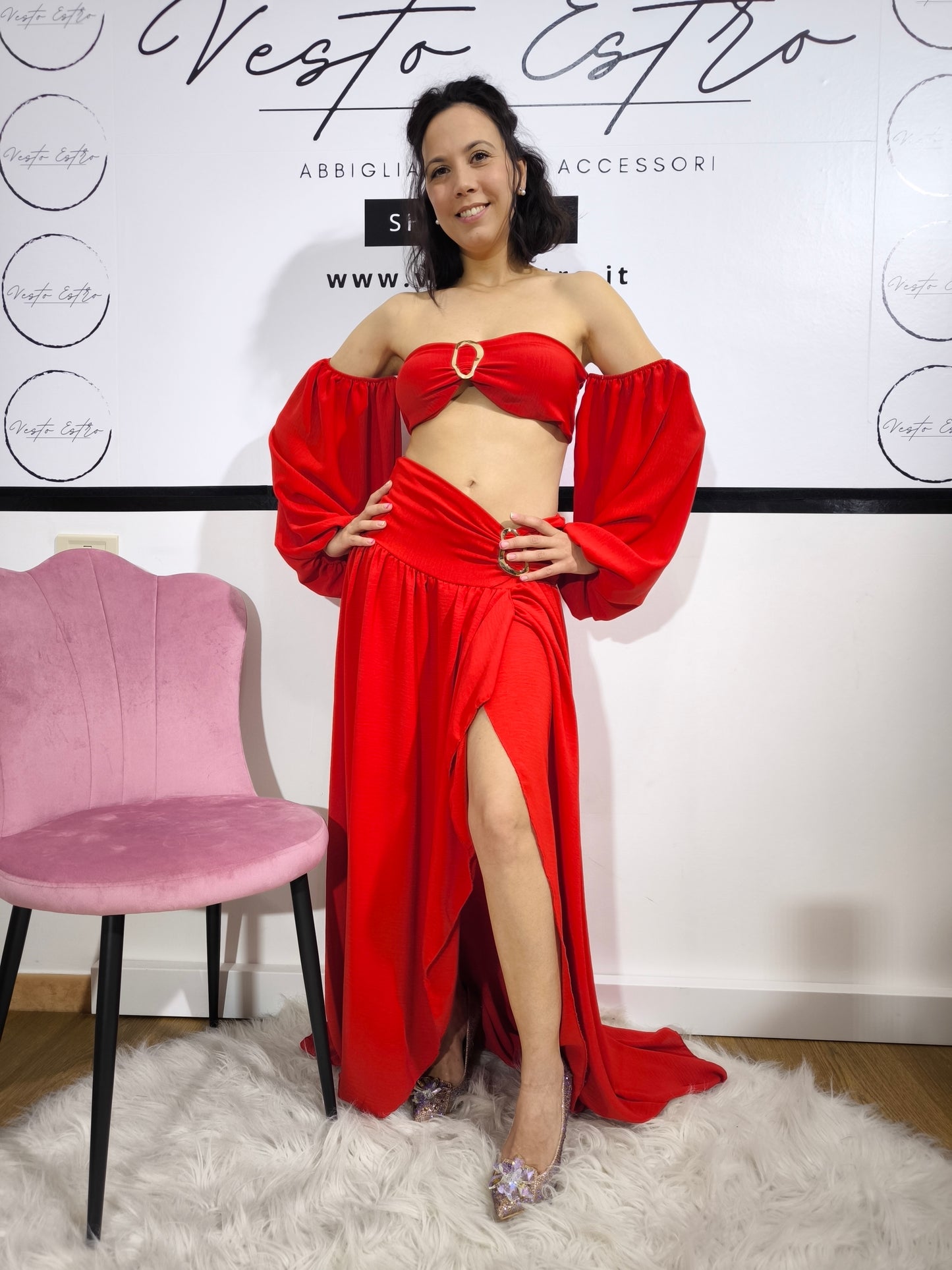 Donna indossa un completo rosso con top a fascia con maniche a palloncino e gonna lunga con spacco laterale – outfit elegante Vesto Estro.