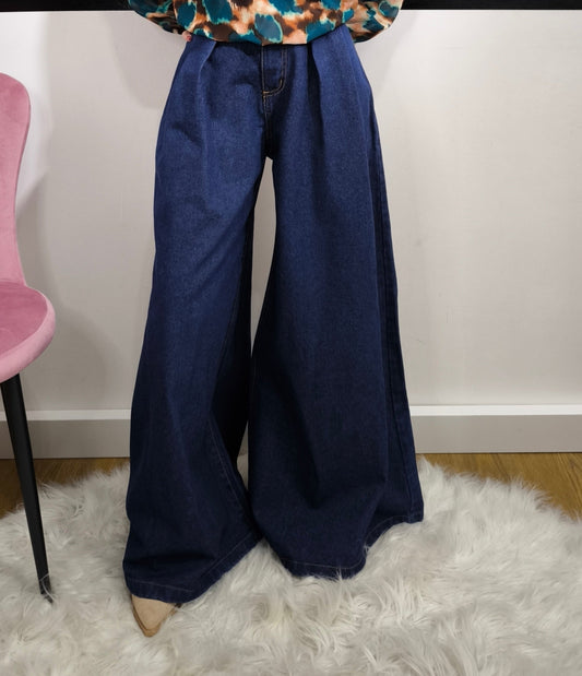Jeans ampio a vita alta da donna in denim blu, stile palazzo, fotografato su tappeto bianco.